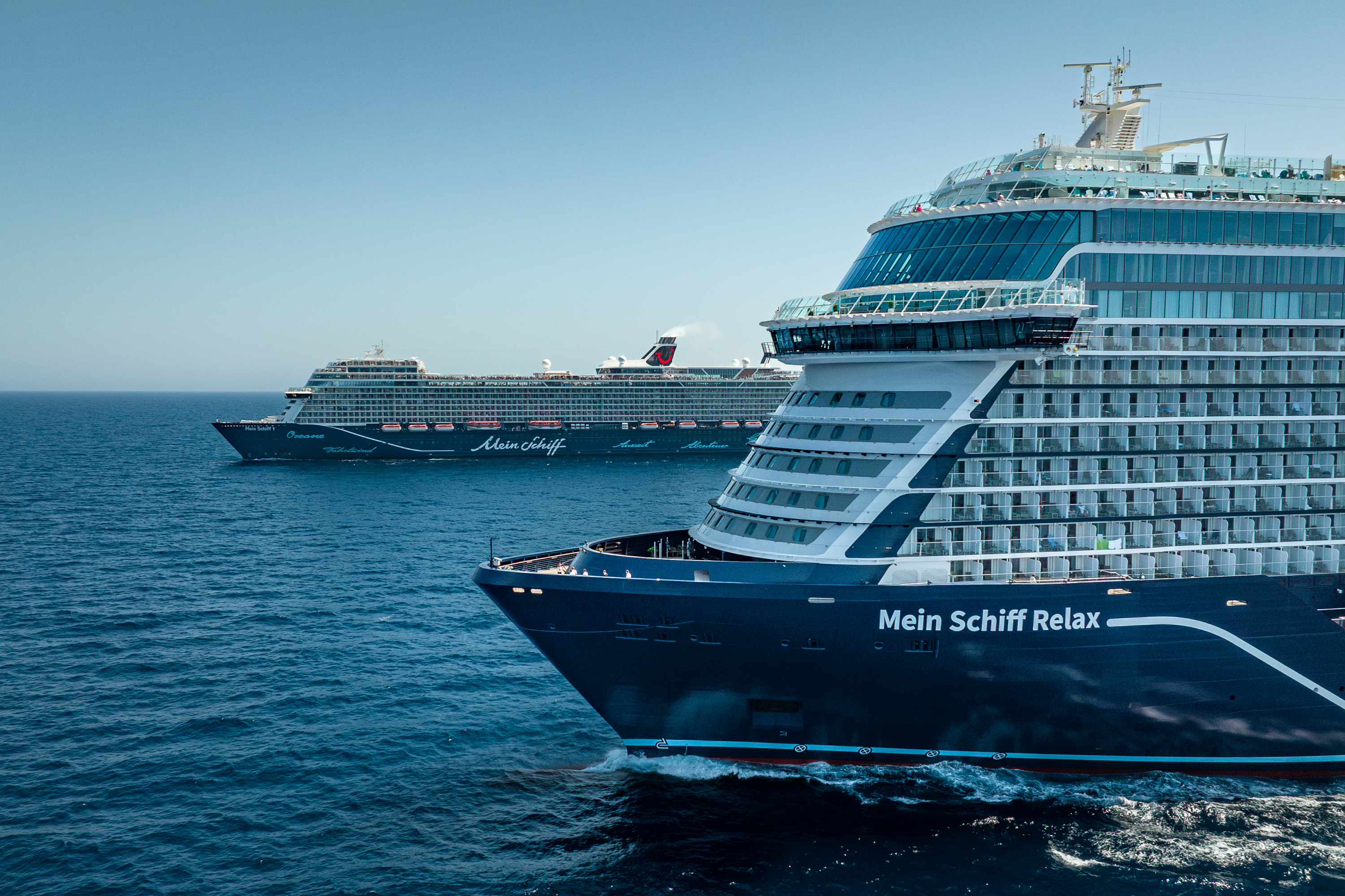 Zwei Kreuzfahrtschiffe der Mein Schiff® Flotte auf offenem Meer.