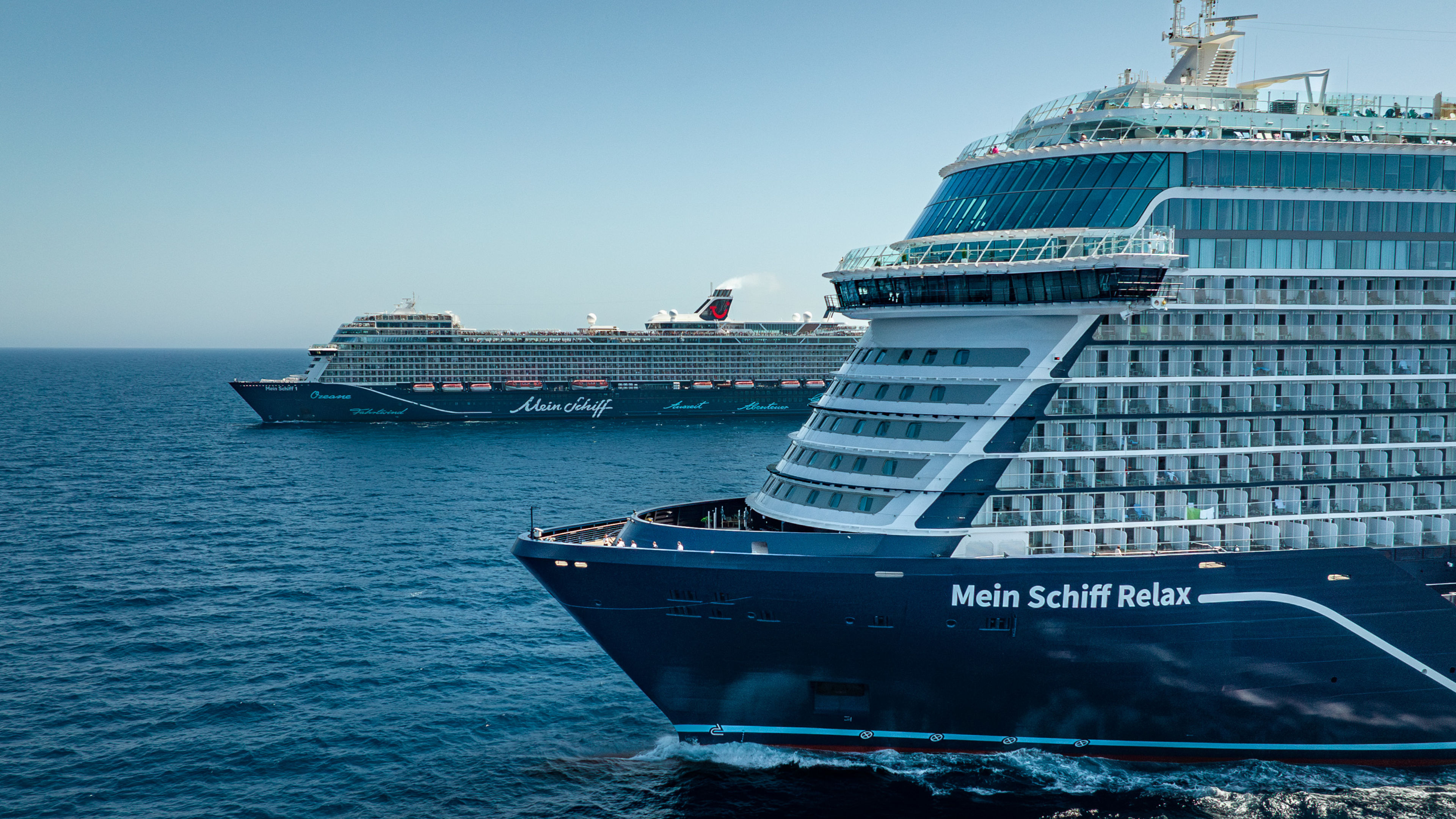 Zwei Kreuzfahrtschiffe der Mein Schiff® Flotte auf offenem Meer. Zwei Kreuzfahrtschiffe der Mein Schiff® Flotte auf offenem Meer.