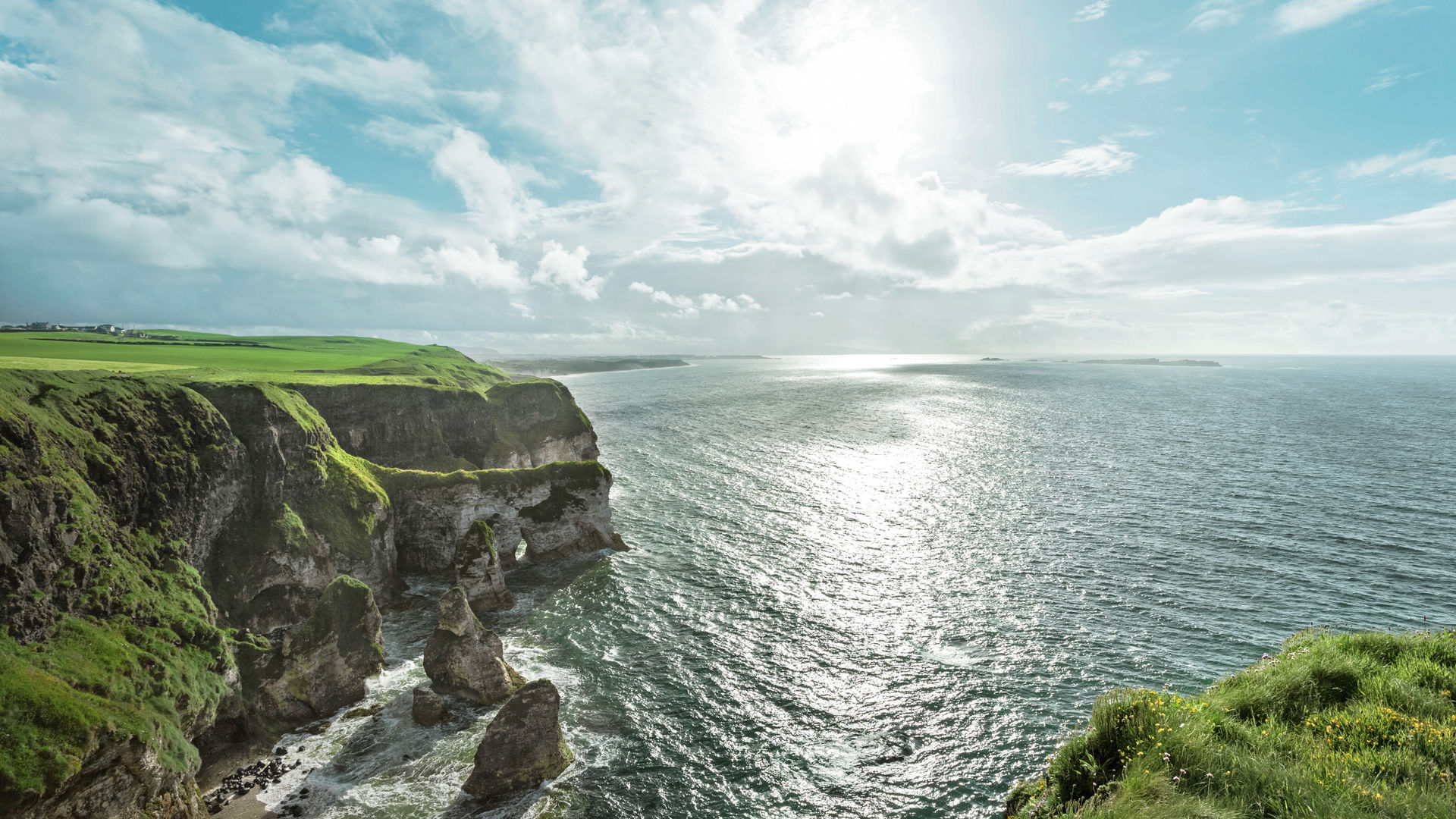 Grüne Klippen und Meer unter bewölktem Himmel, Irland.