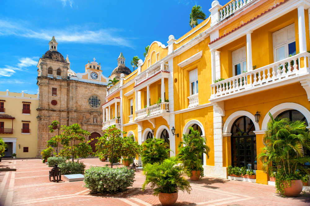 Gelbes Kolonialgebäude und Kirche in Cartagena, blauer Himmel.