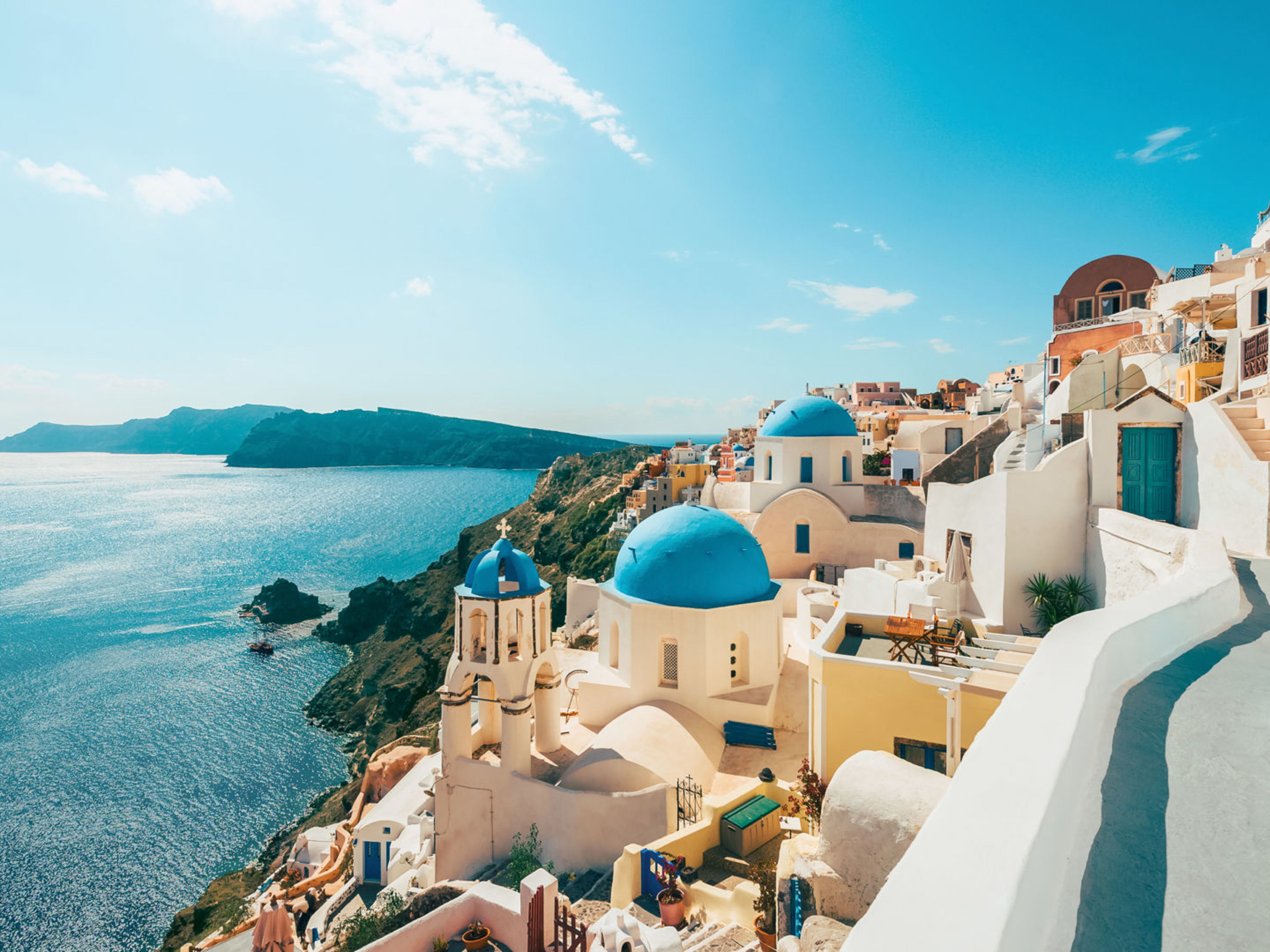 Santorini Griechenland Kreuzfahrt Santorini, weiße Gebäude, blaue Kuppeln, Meerblick, sonniger Himmel.