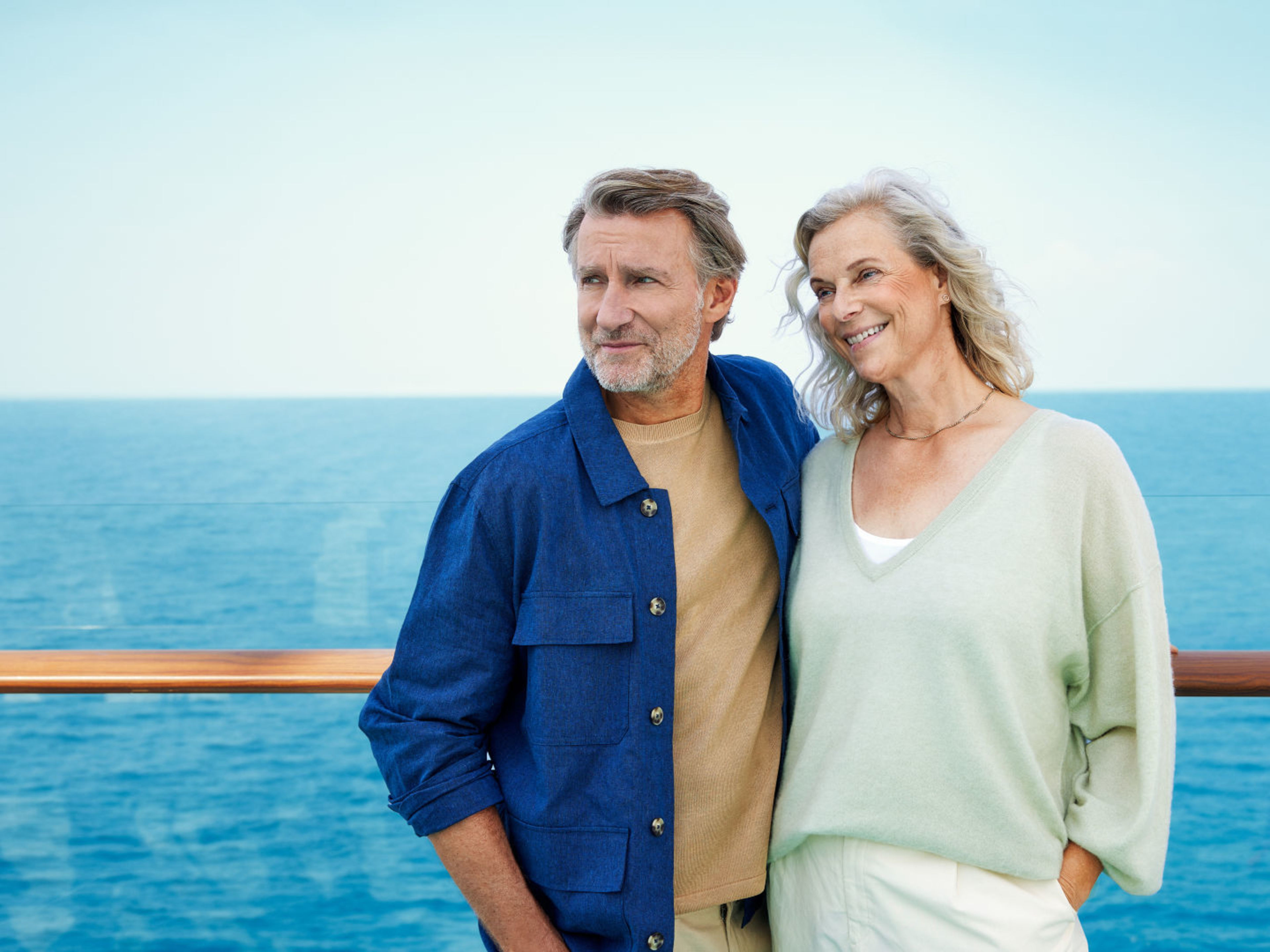 Paar auf dem Außendeck Paar auf Kreuzfahrtschiff, lächelnd, blauer Himmel, Meereshorizont.
