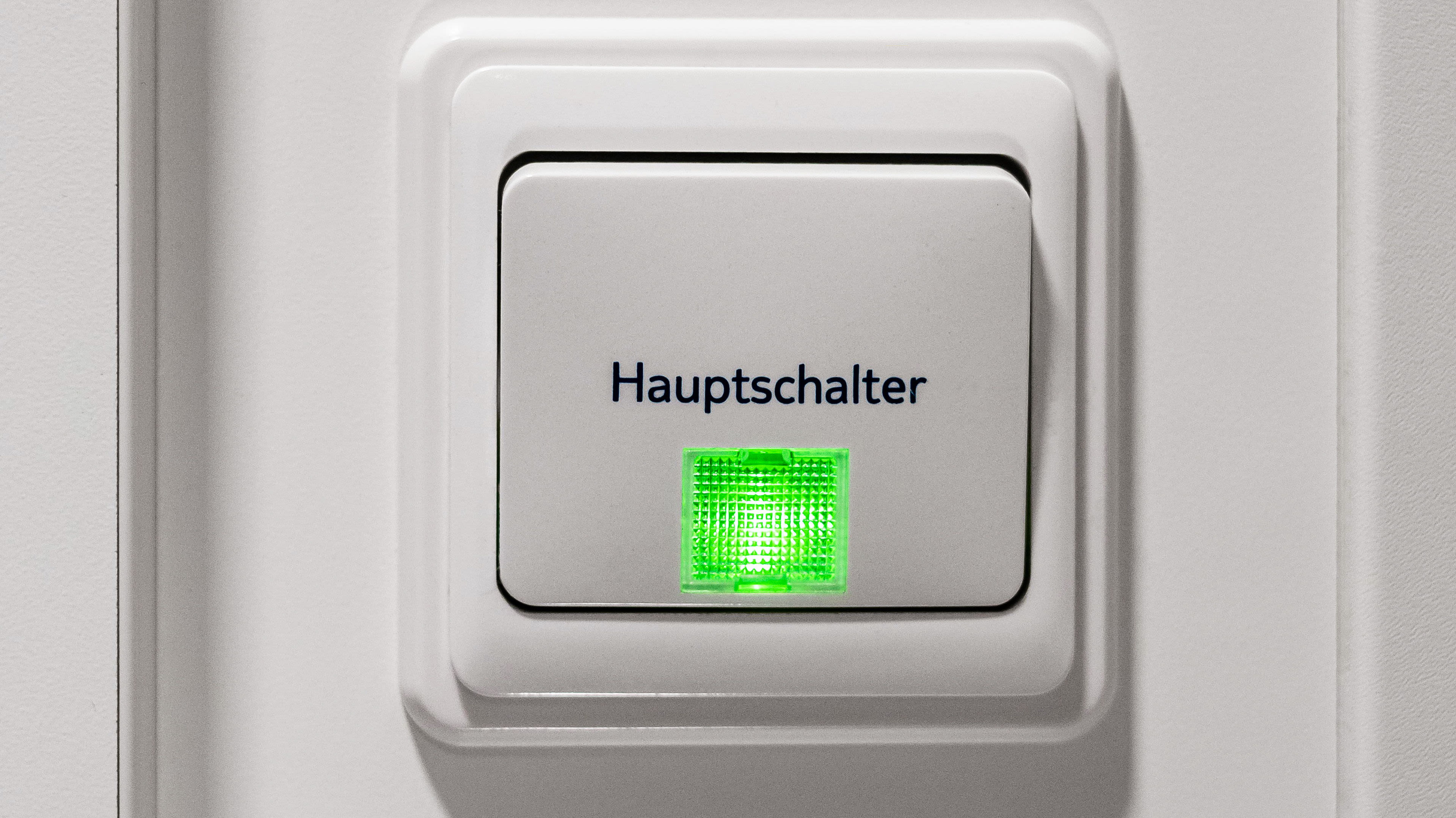 Weißer Hauptschalter mit grünem Licht, Nahaufnahme.