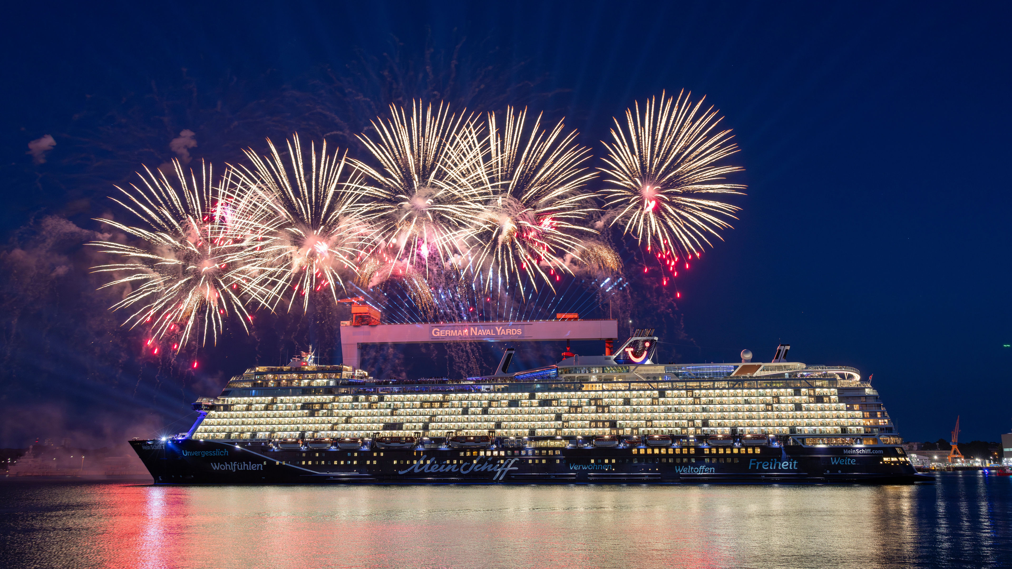 Kreuzfahrtschiff der Mein Schiff® Flotte vor Feuerwerk bei Nacht.