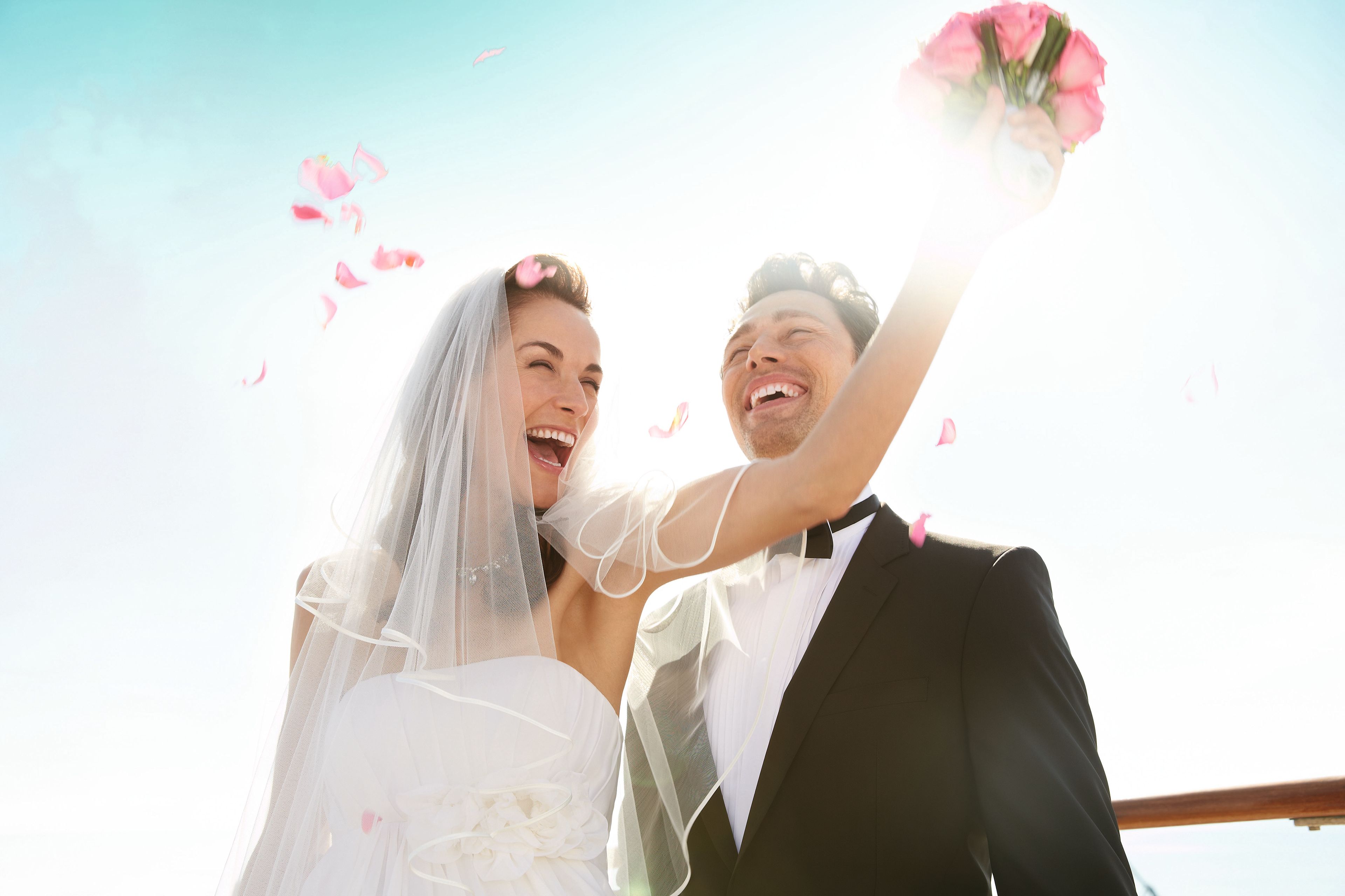 Lachendes Brautpaar mit Blumenstrauß und Sonnenlicht. Lachendes Brautpaar mit Blumenstrauß und Sonnenlicht.