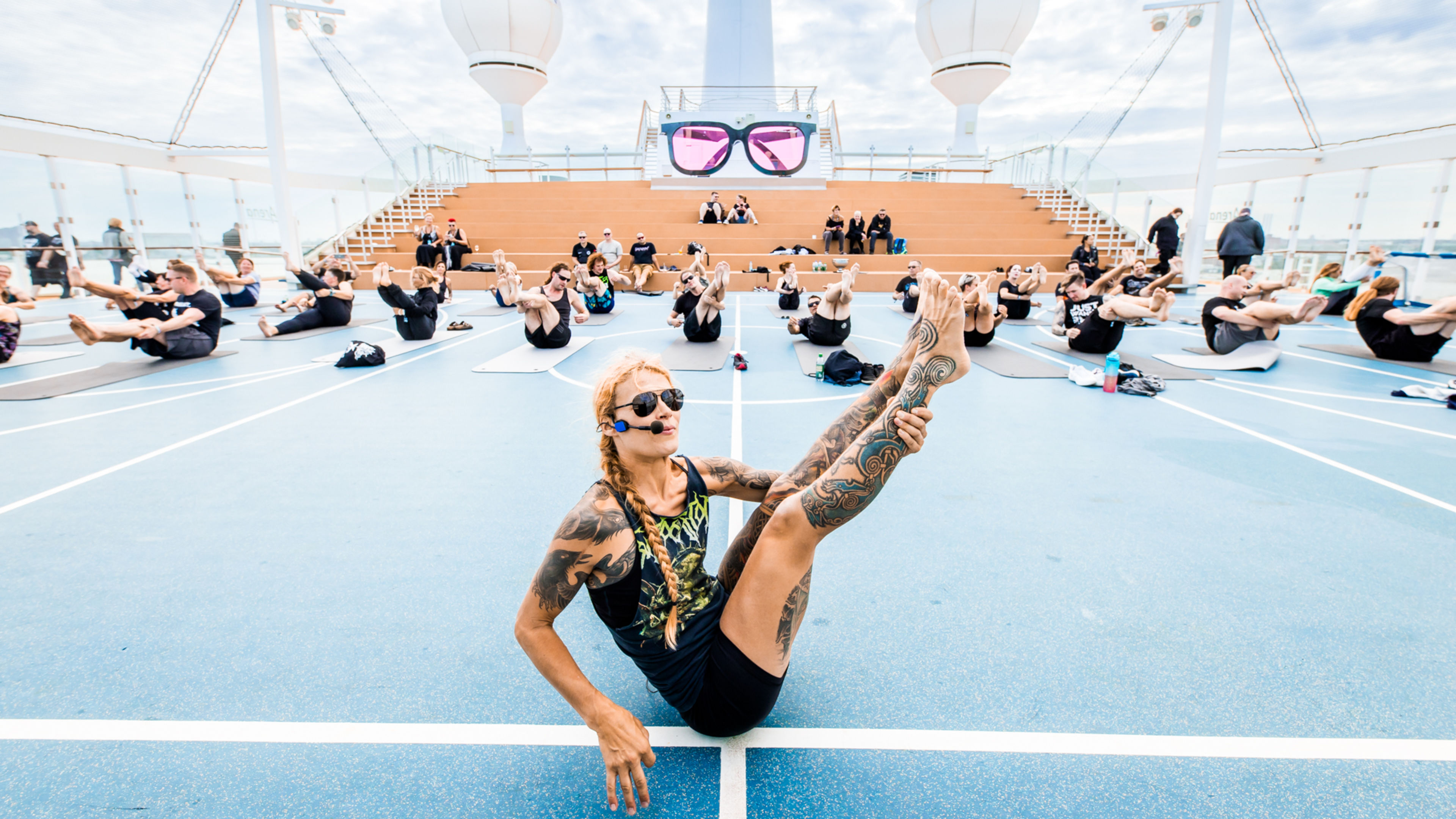 Atmo @ Full Metal Cruise 21.09.2023 @vollvincent-7440 Menschen machen Yoga auf Kreuzfahrtschiffdeck, blauer Himmel, Sonnenbrillen.