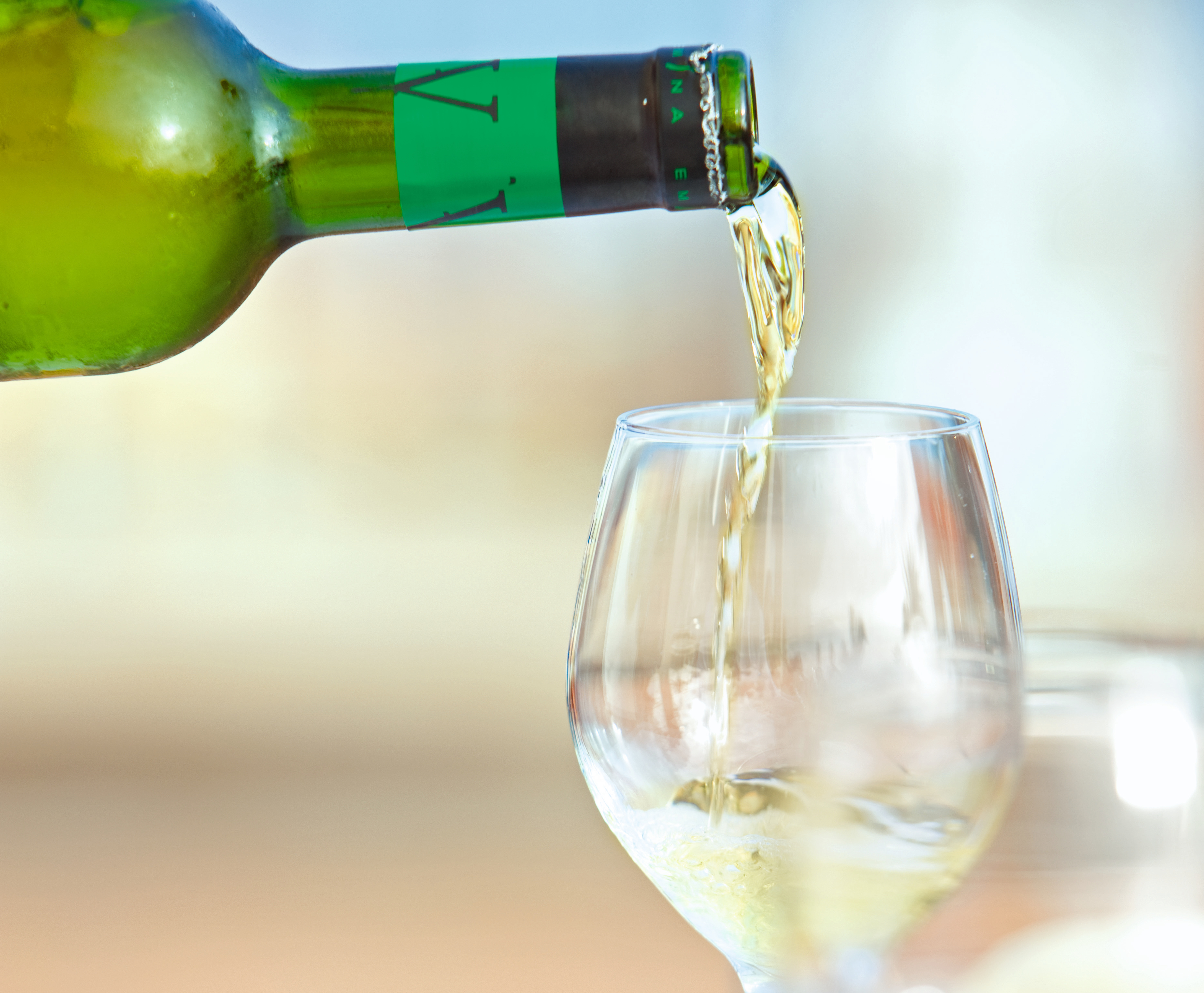 Weißwein wird in ein Glas gegossen.