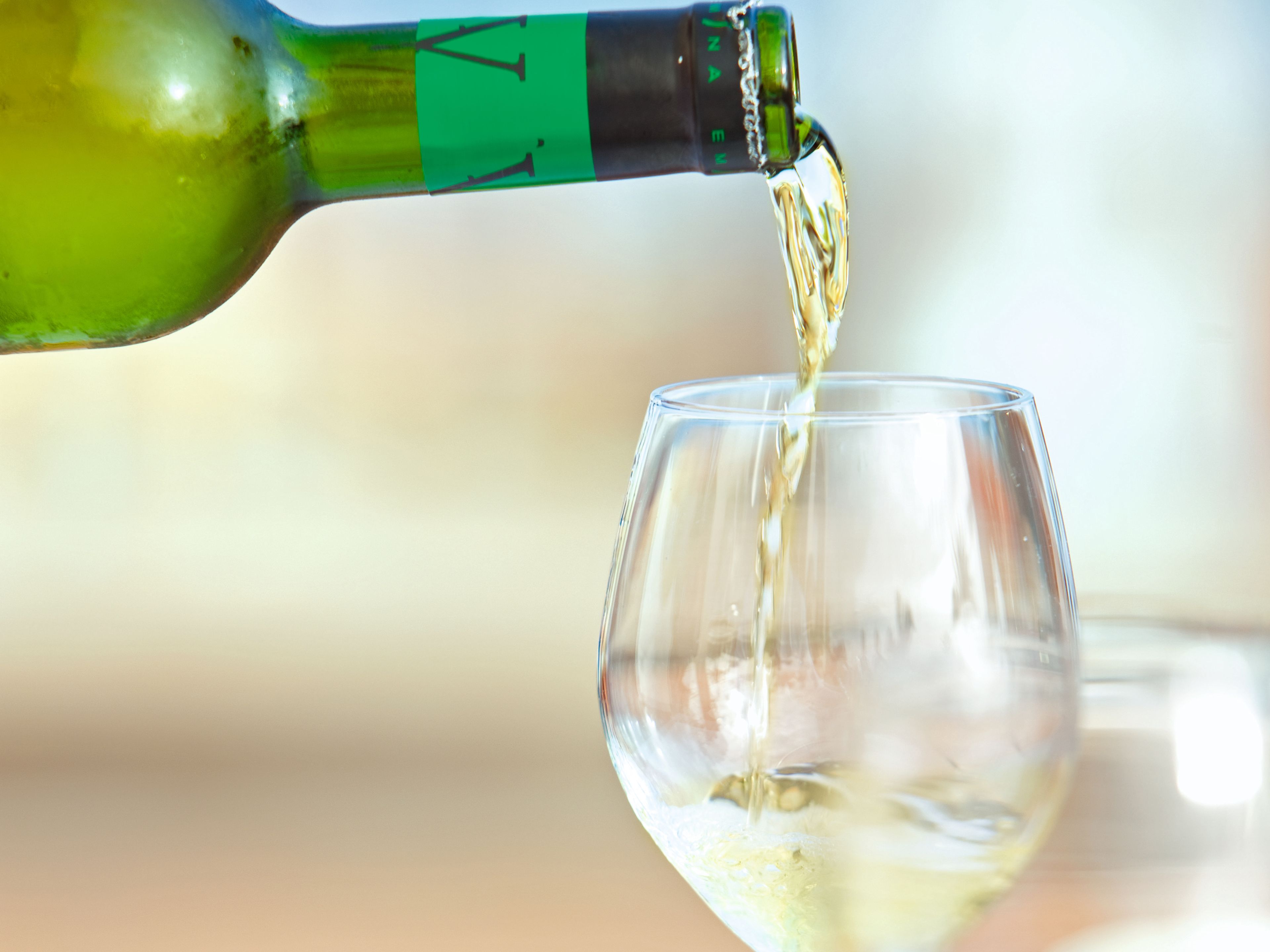 Weißwein wird in ein Glas gegossen. Weißwein wird in ein Glas gegossen.