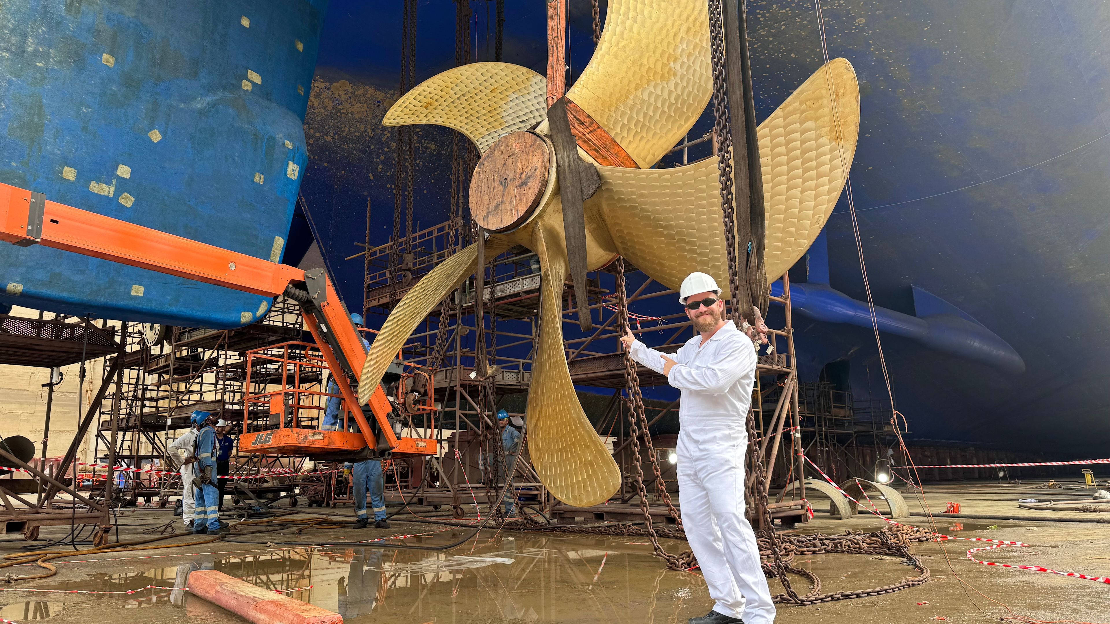 Jan Fortun im Drydock in Dubai Mann in weißem Overall vor großem Schiffspropeller in Werft.