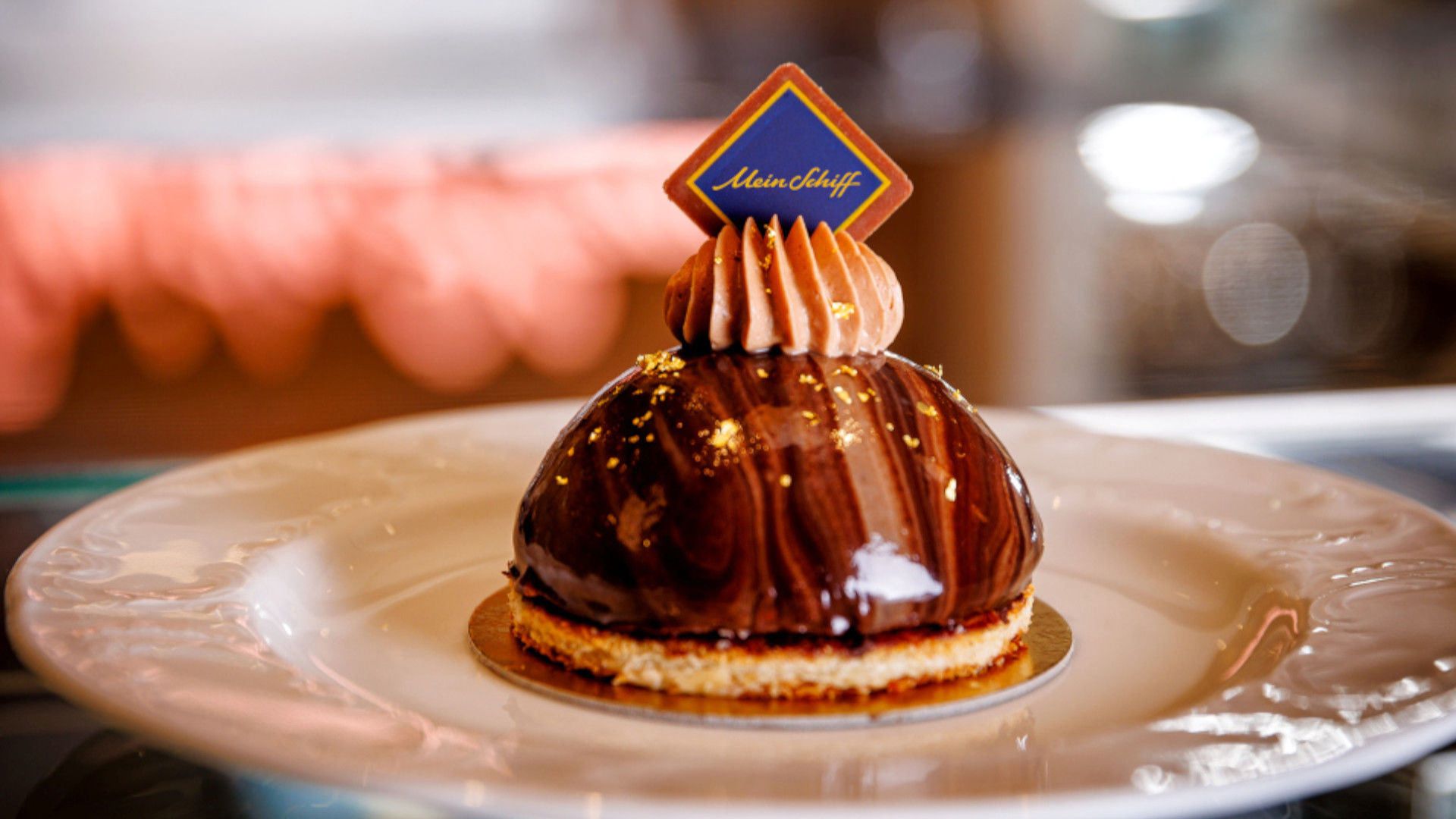 Schokoladendessert mit goldenen Akzenten und Mein Schiff® Logo.