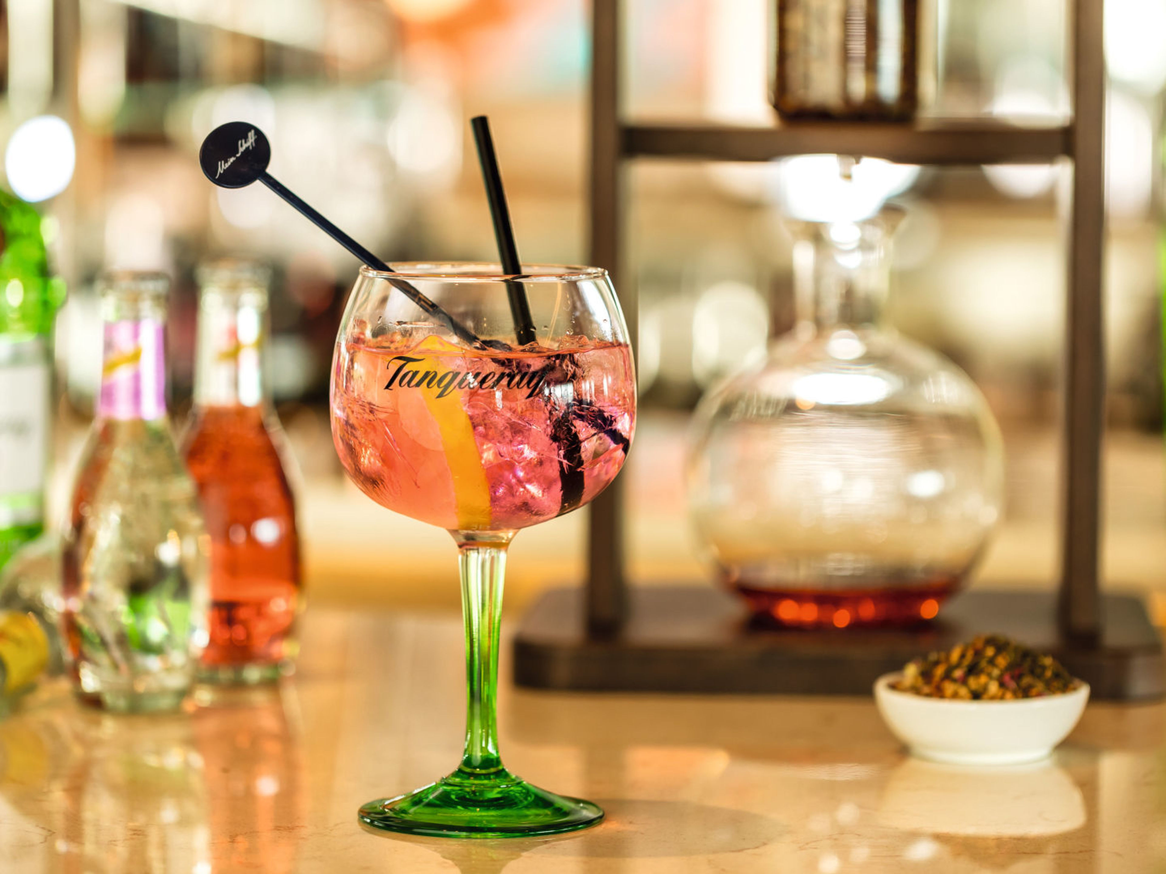 100 hochwertige Markengetränke Cocktailglas mit rosa Getränk, Zitronenscheibe, Barhintergrund.