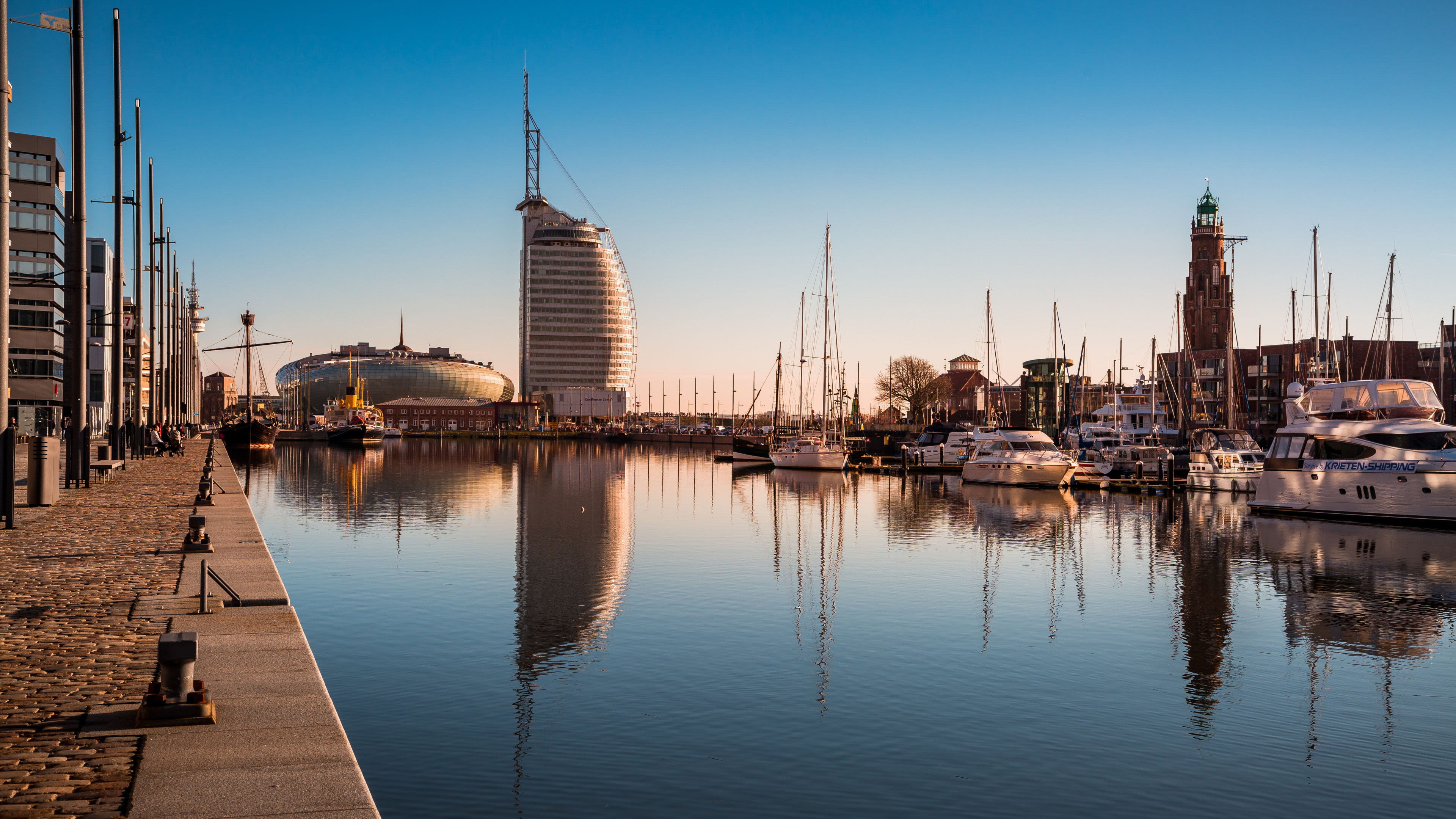 Bremerhaven Hafen mit Segelbooten, modernem Gebäude und klarem Himmel.