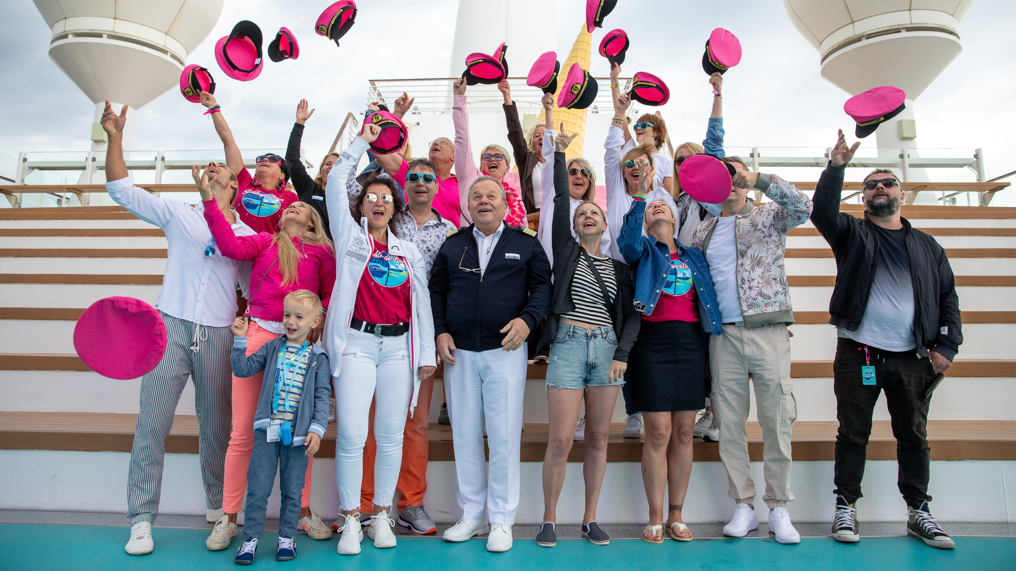 Gruppe wirft pinke Hüte in die Luft auf Kreuzfahrtschiff.