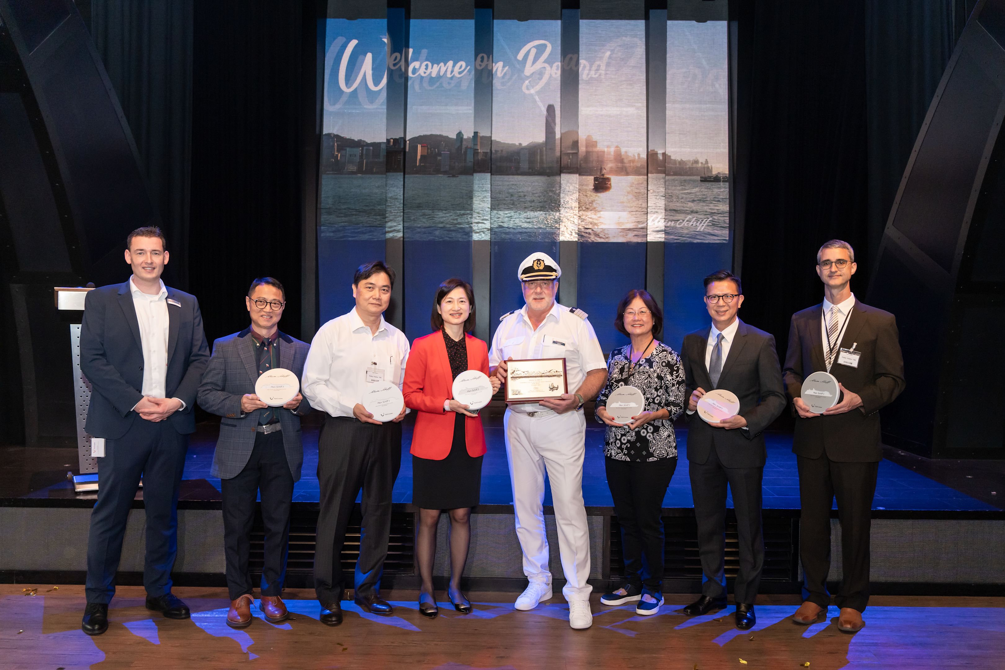 Gruppe von acht Personen mit Auszeichnungen auf einer Bühne.