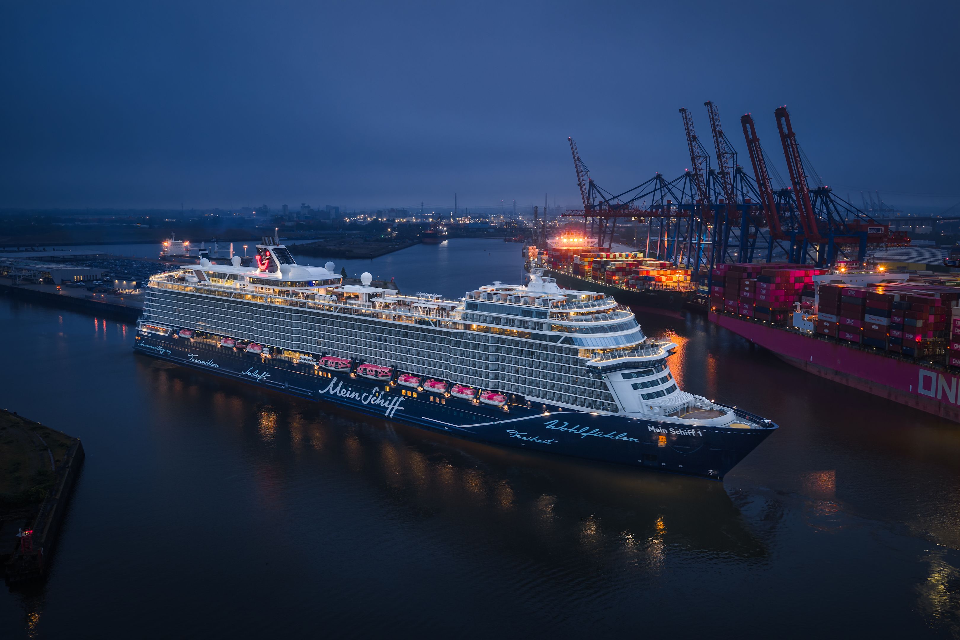 Kreuzfahrtschiff der Mein Schiff® Flotte im Hafen bei Nacht, beleuchtet.