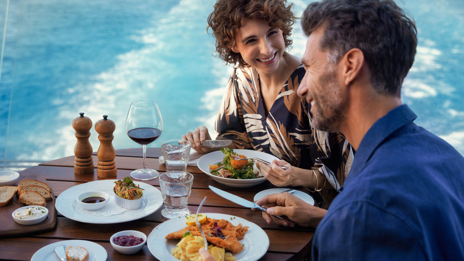Paar genießt Mittagessen auf Kreuzfahrtschiff, Meerblick, Wein.