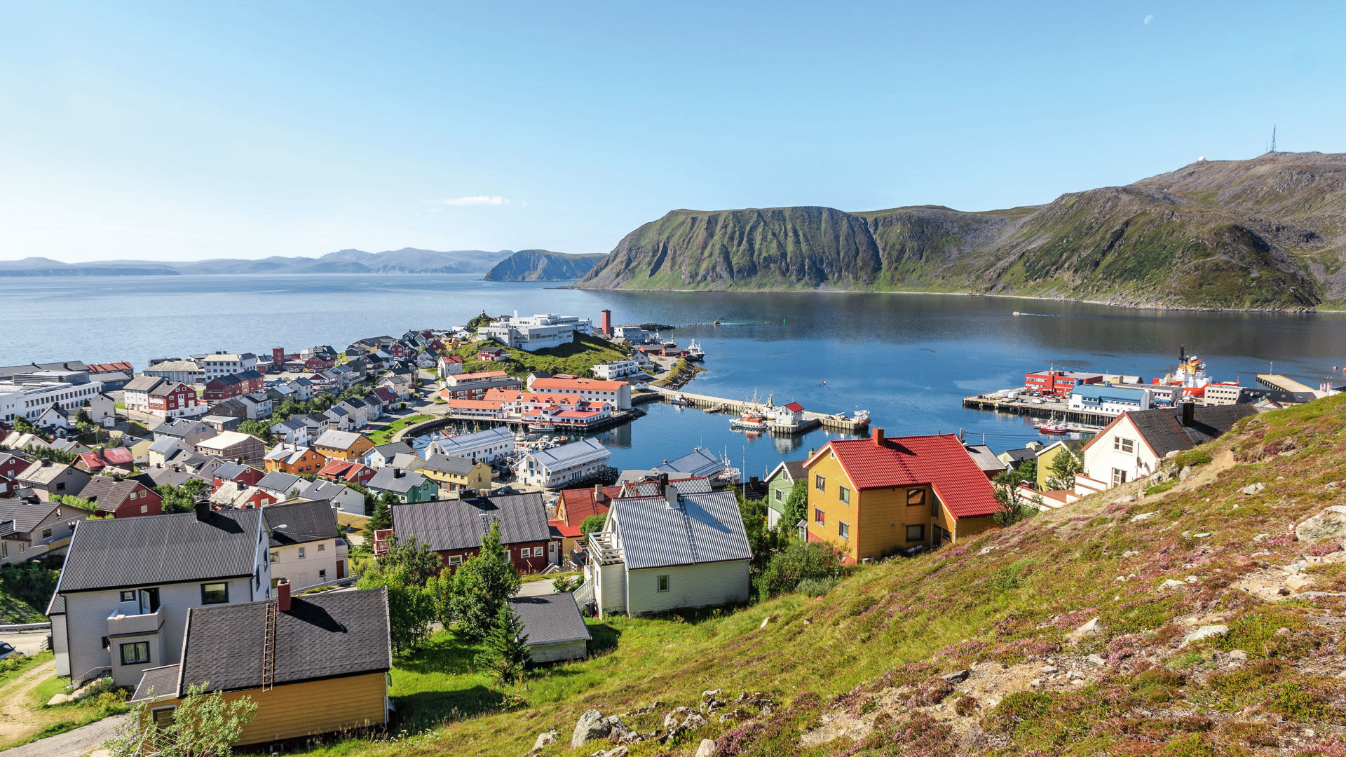 Bunte Häuser und Hafen in Honningsvåg, Norwegen, umgeben von Bergen und Meer.