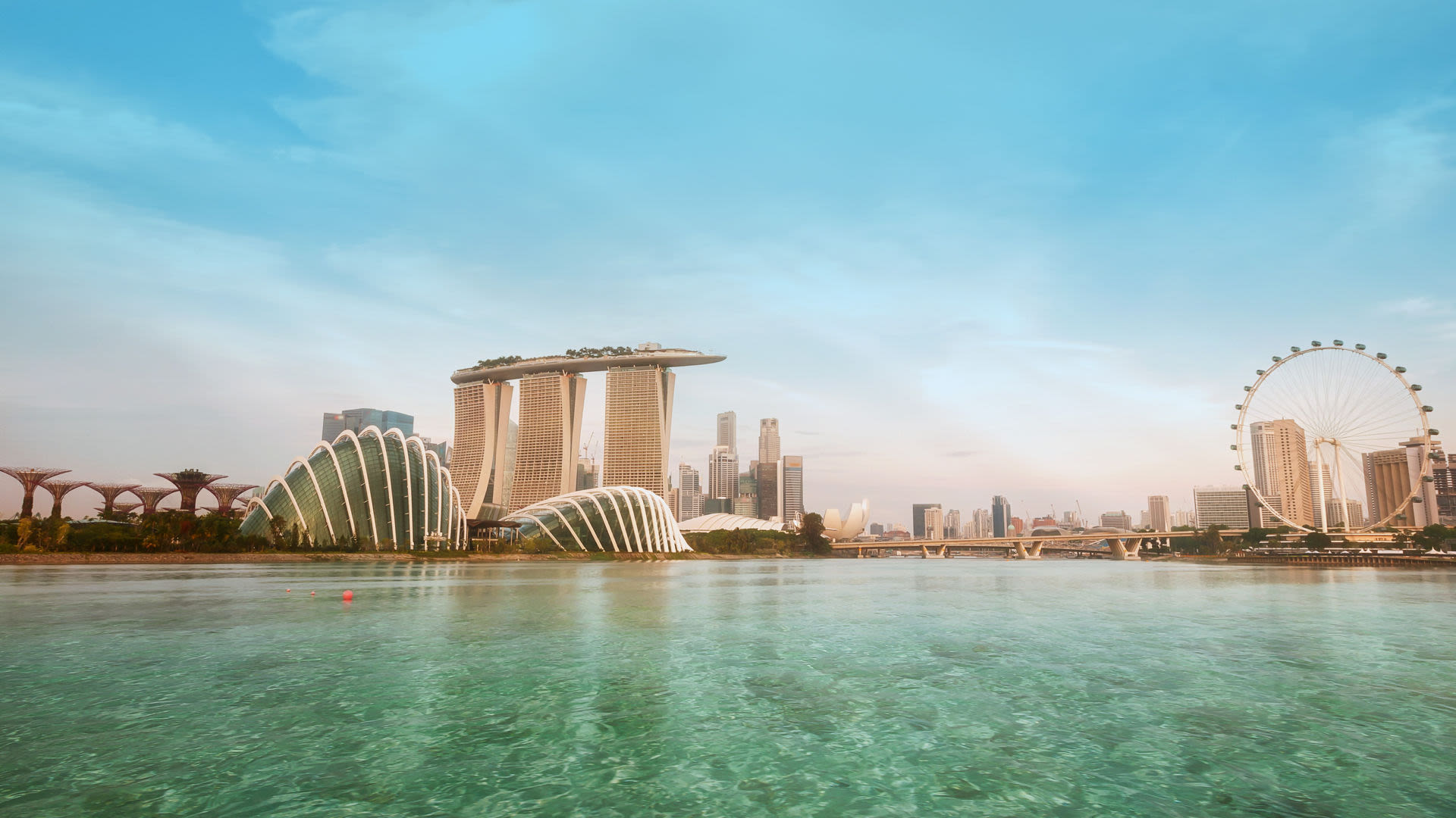 Singapur Skyline mit Marina Bay Sands, Riesenrad und blauem Himmel.