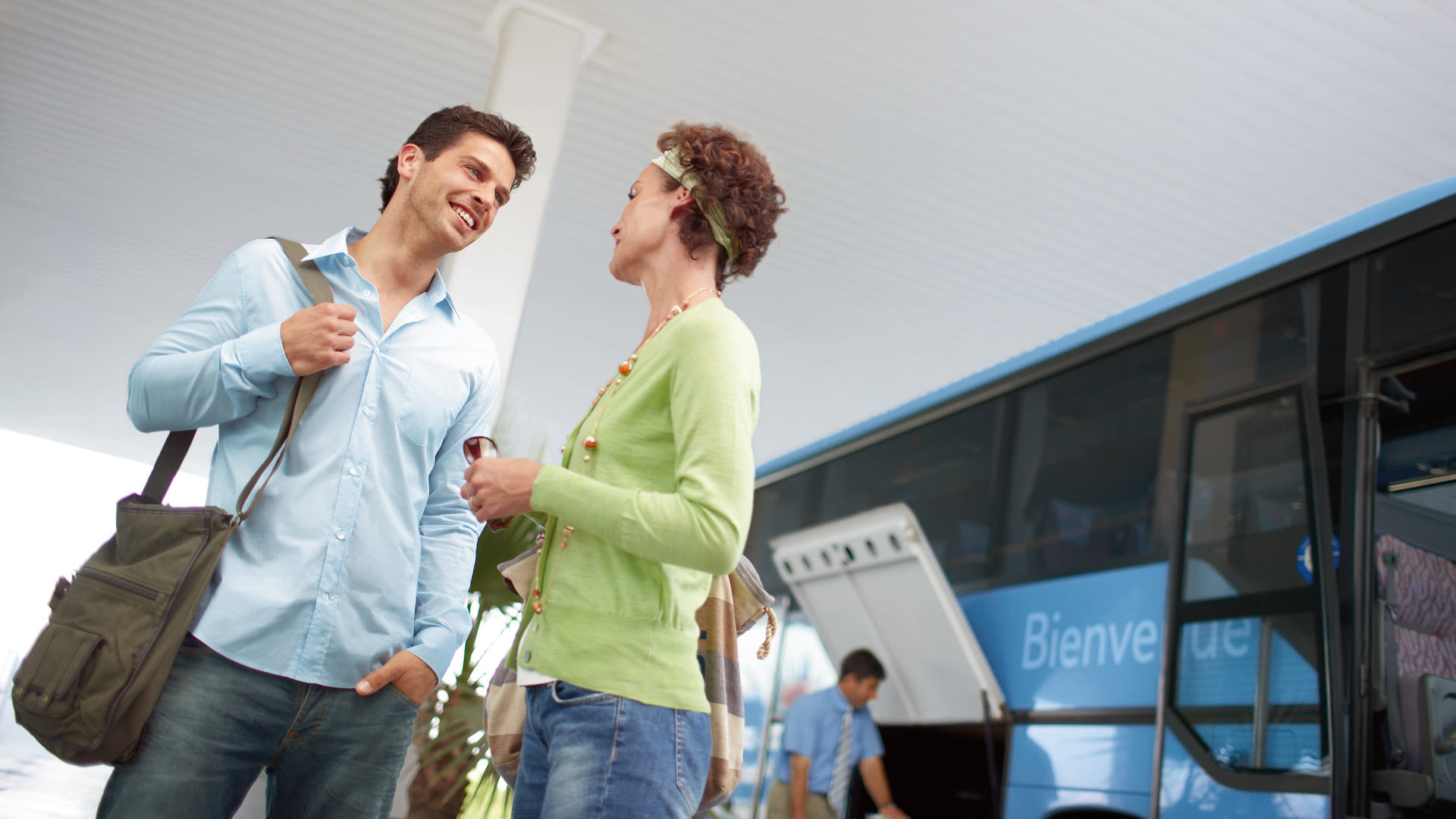 Zwei Personen unterhalten sich vor einem blauen Reisebus.