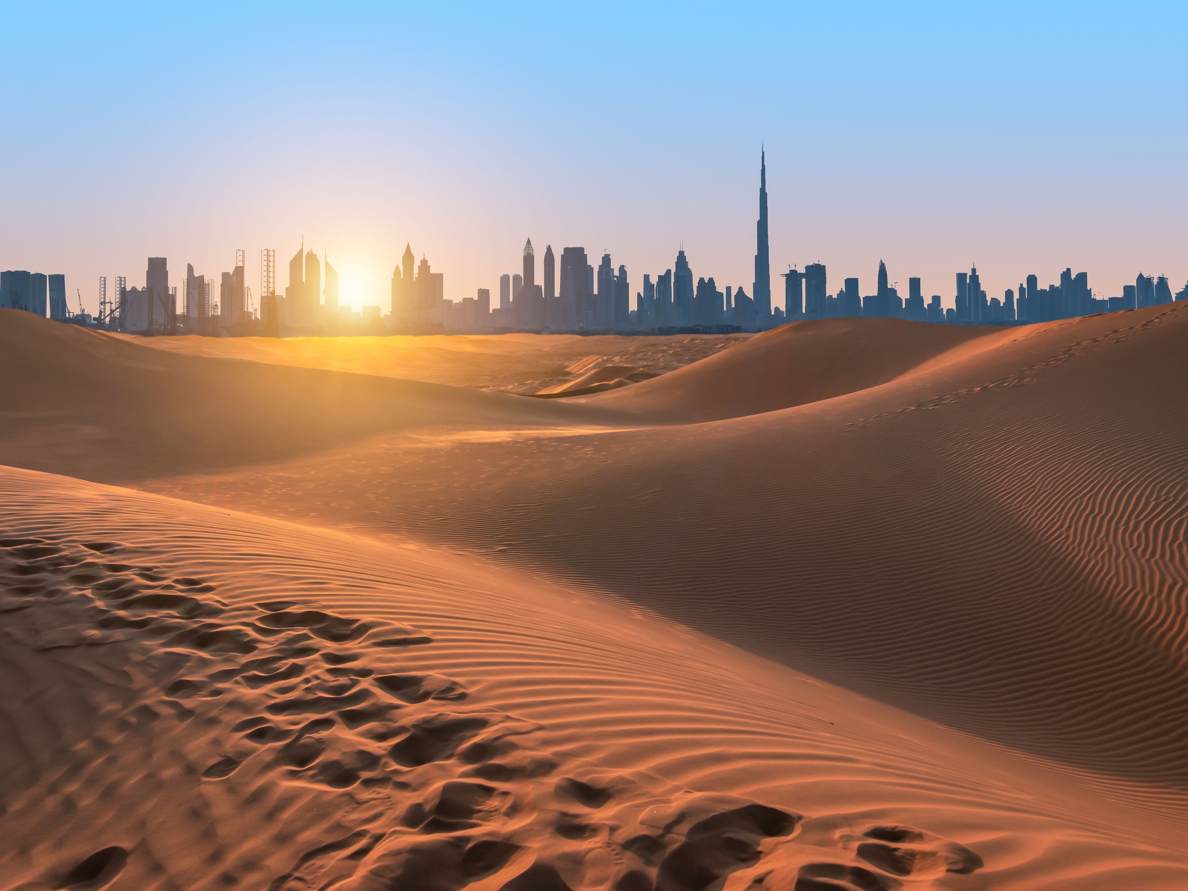 Destinationsmotiv, Dubai, UAE Wüstenlandschaft bei Sonnenuntergang, Dubai Skyline im Hintergrund.