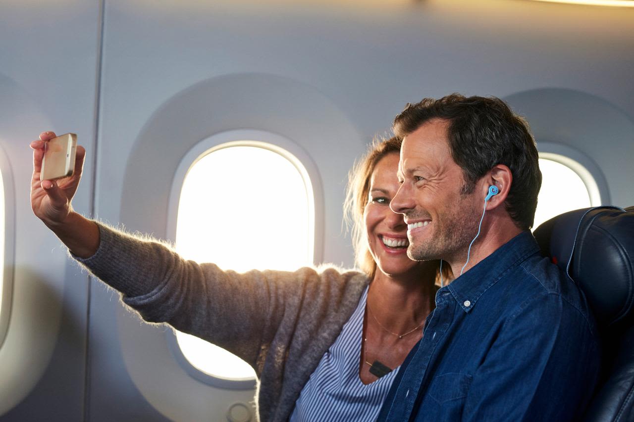 Flug Paar macht Selfie im Flugzeug, lächelnd, Sonnenlicht durch Fenster.