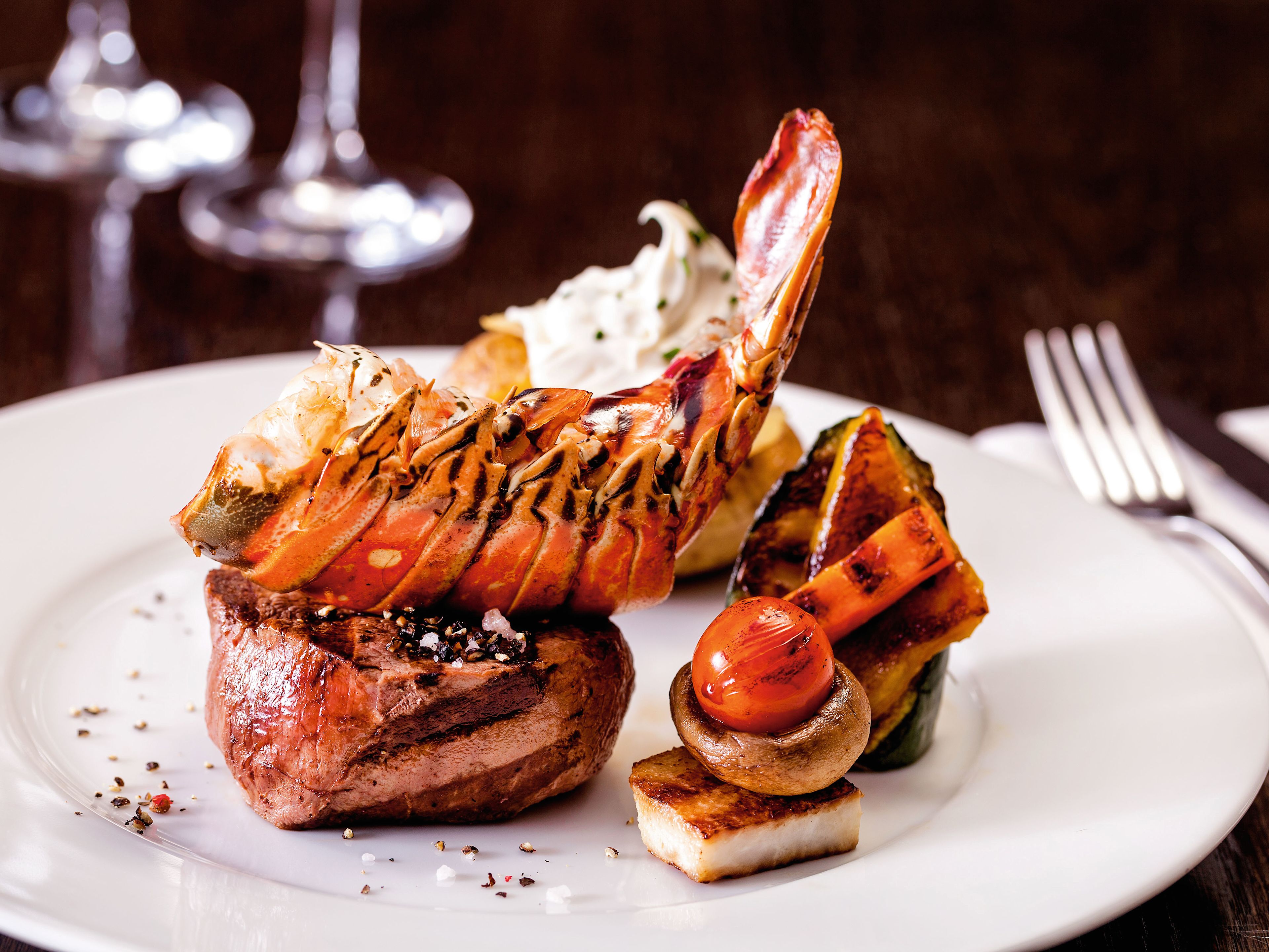 Atlantik_Klassik Hummer und Steak auf weißem Teller mit Gemüse.