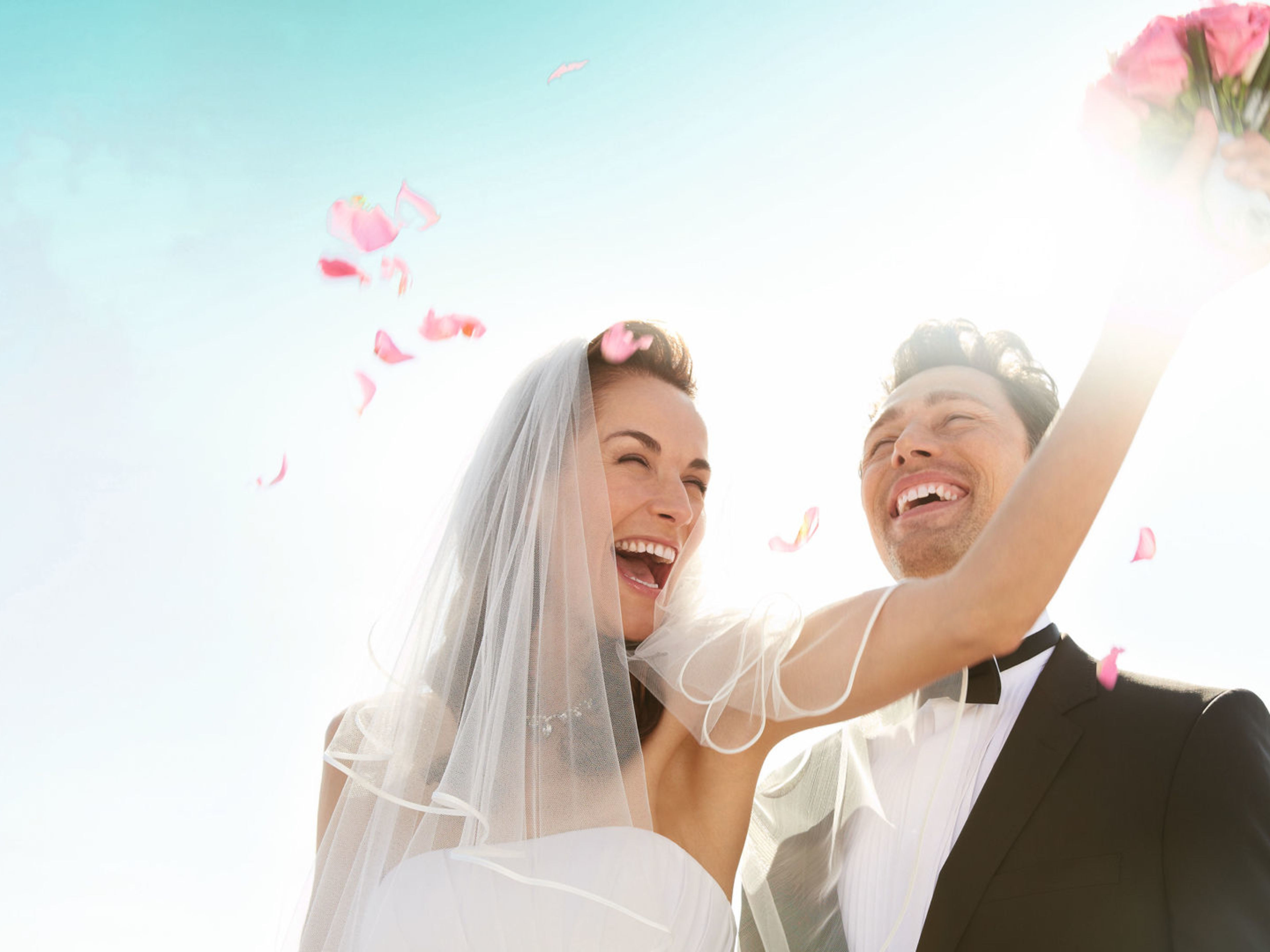 Hochzeit an Bord Lachendes Brautpaar im Sonnenlicht mit Blumenstrauß.