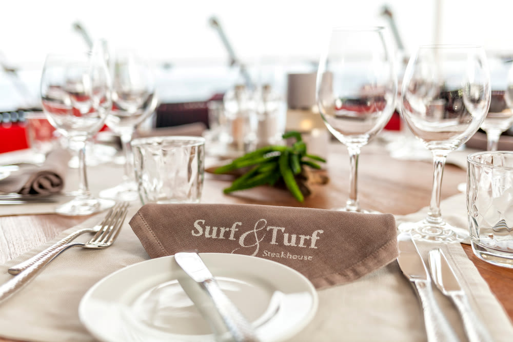 Gedeckter Tisch im Surf & Turf Steakhouse mit Gläsern und Besteck.