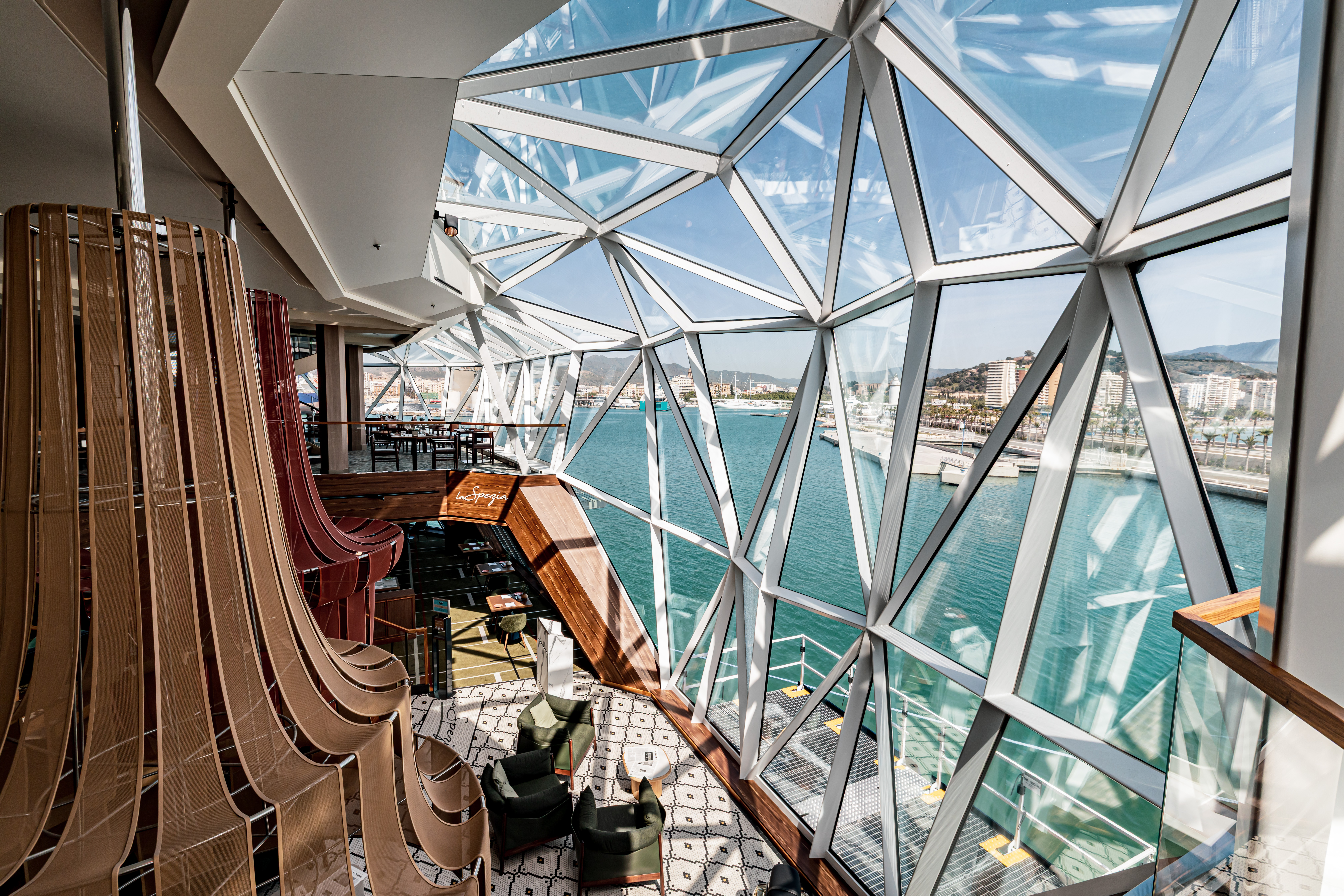 Modernes Kreuzfahrtschiff-Interieur mit Panoramafenstern, Blick auf Hafen und Meer.