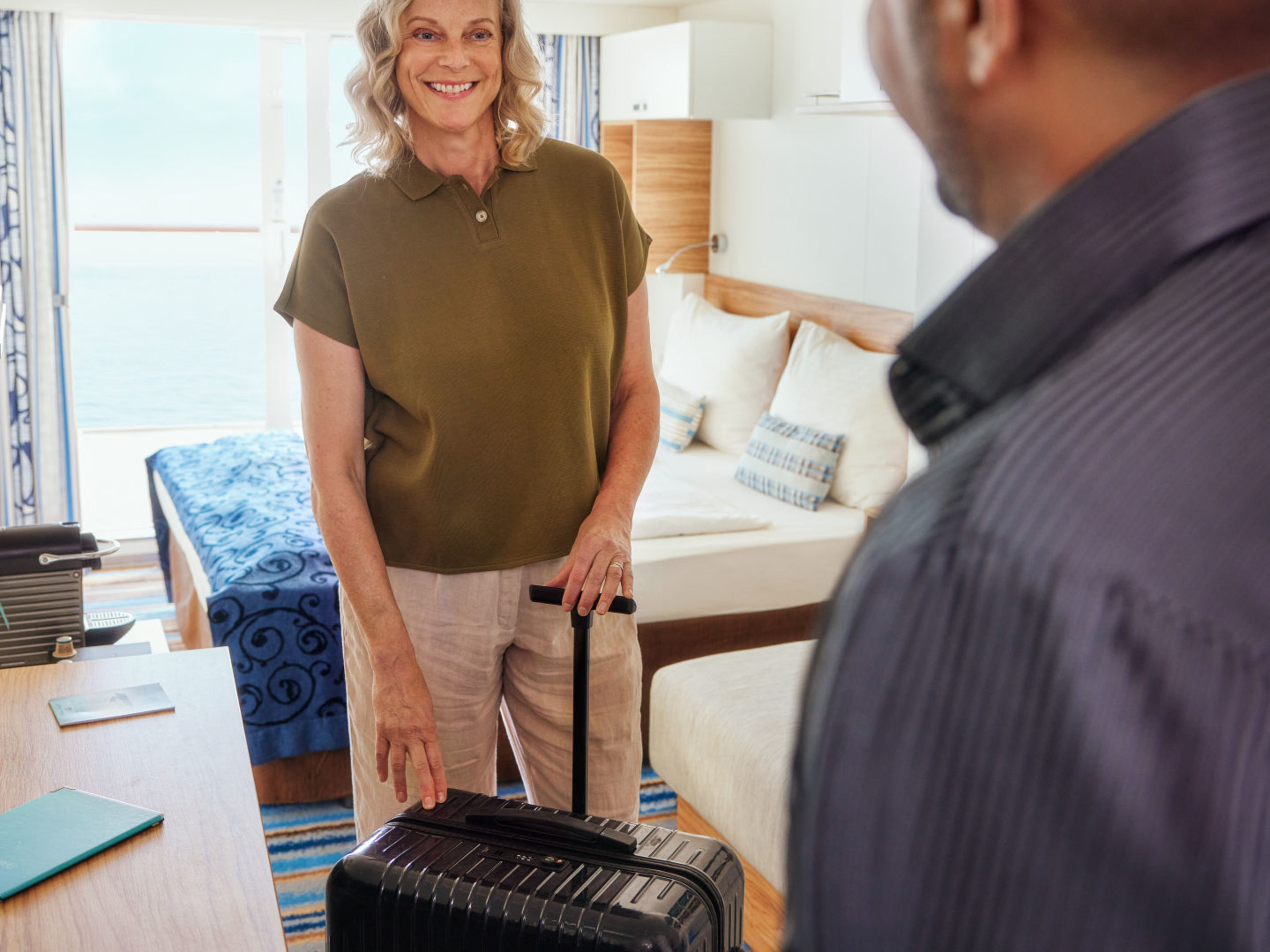 Frau mit Koffer in Kreuzfahrtschiff-Kabine, lächelnd, Meerblick. Frau mit Koffer in Kreuzfahrtschiff-Kabine, lächelnd, Meerblick.