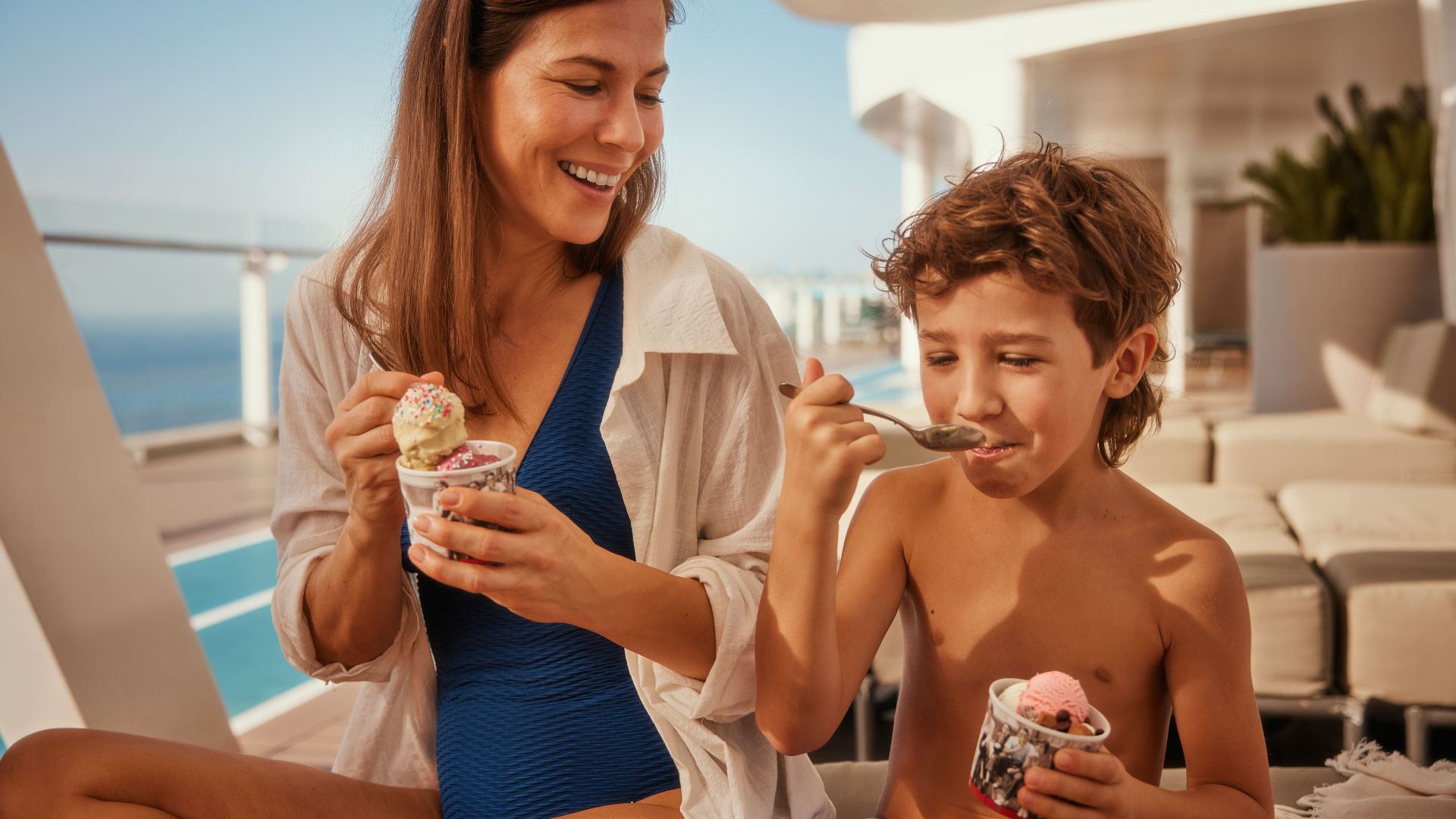 Frau und Kind essen Eis auf Kreuzfahrtschiff, sonniger Tag.