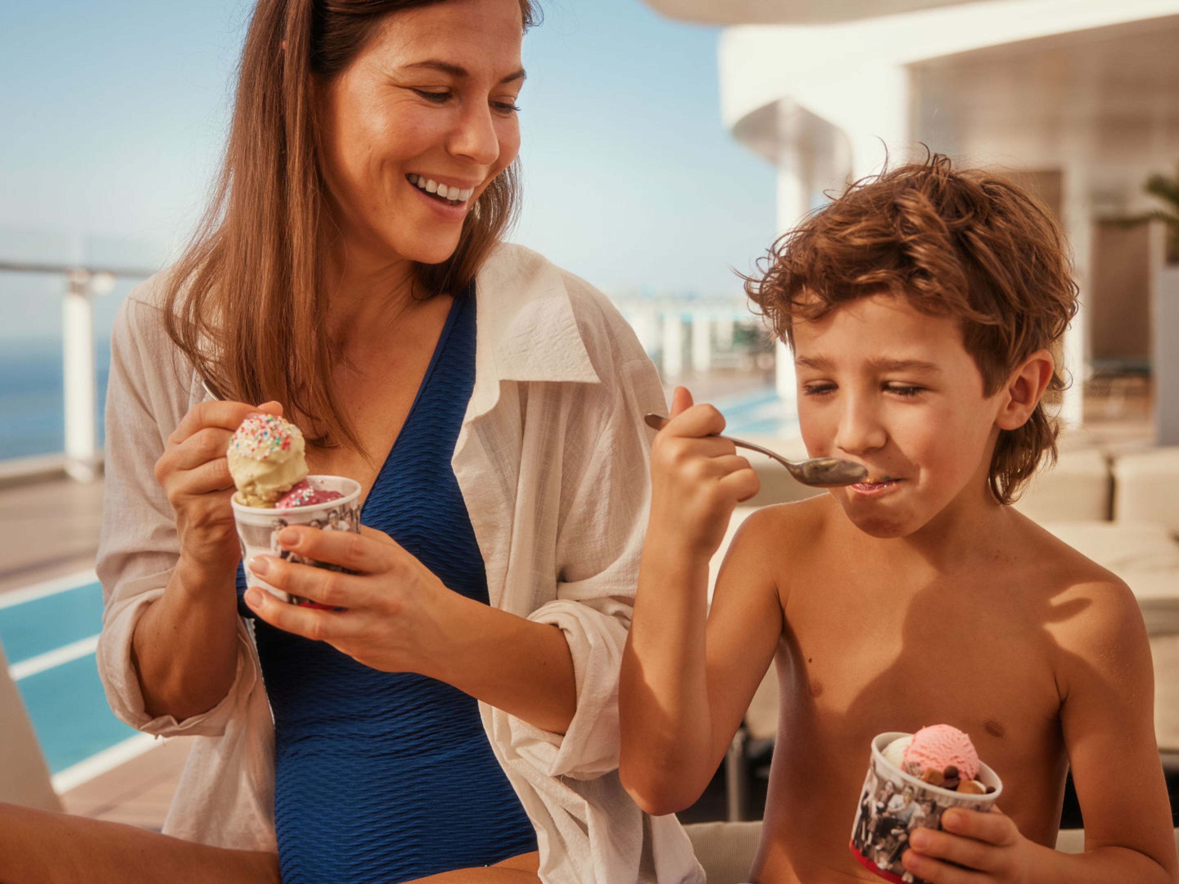 Frau und Kind essen Eis mit Meerblick, sonniger Tag. Frau und Kind essen Eis mit Meerblick, sonniger Tag.