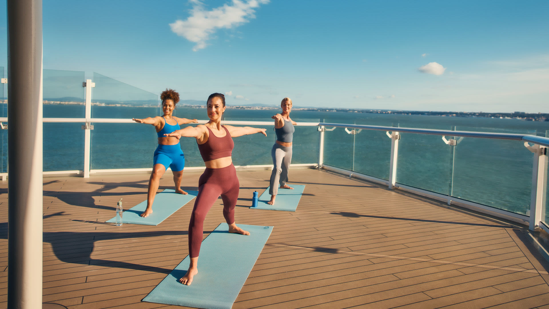Drei Frauen machen Yoga auf einem Kreuzfahrtschiffdeck.