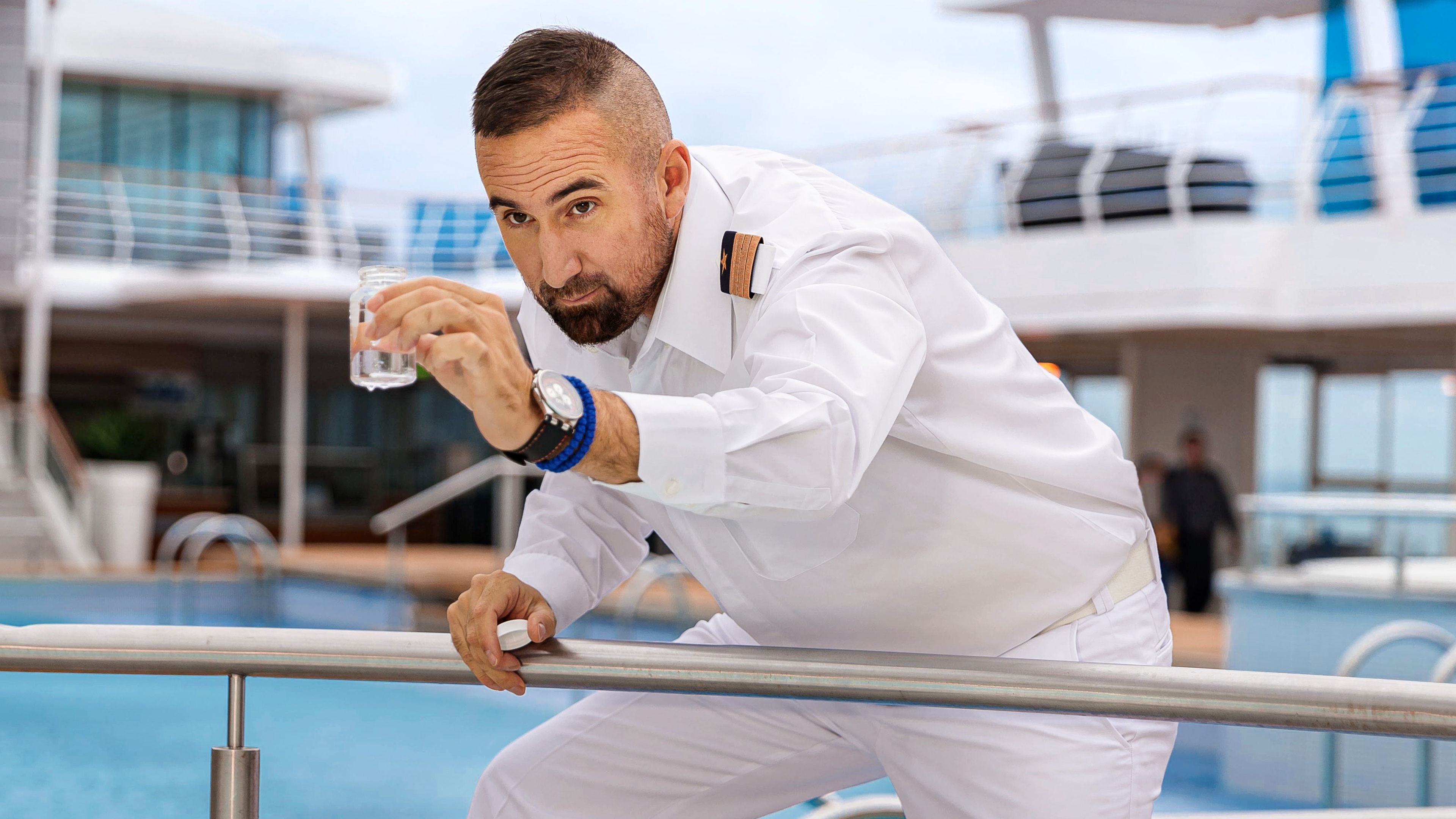 Mann in weißer Uniform prüft Wasser auf Kreuzfahrtschiff.