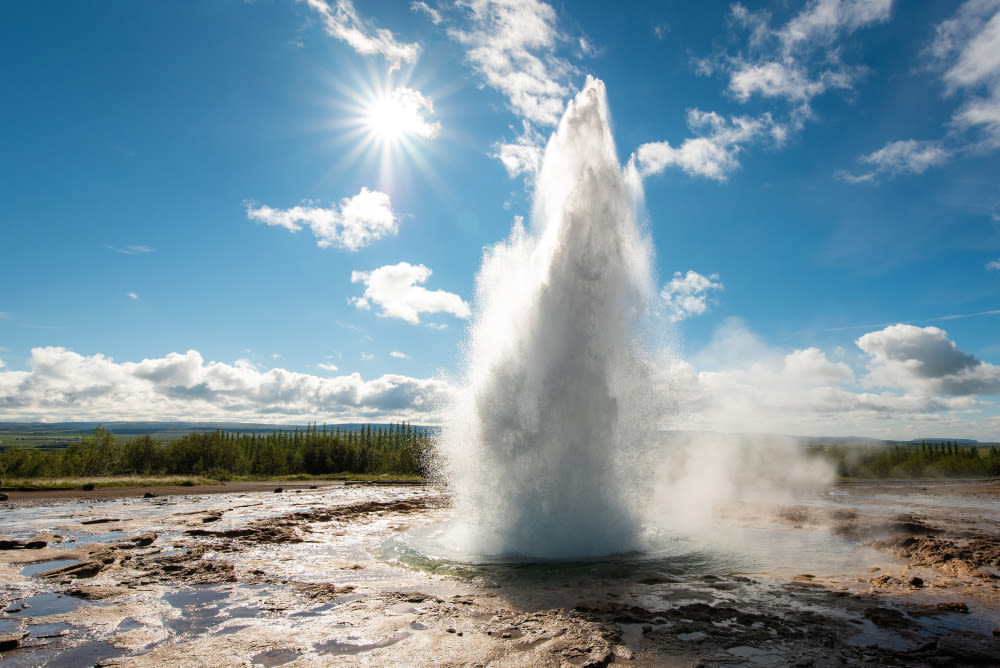 Geysir-Ausbruch unter blauem Himmel mit Sonnenschein.