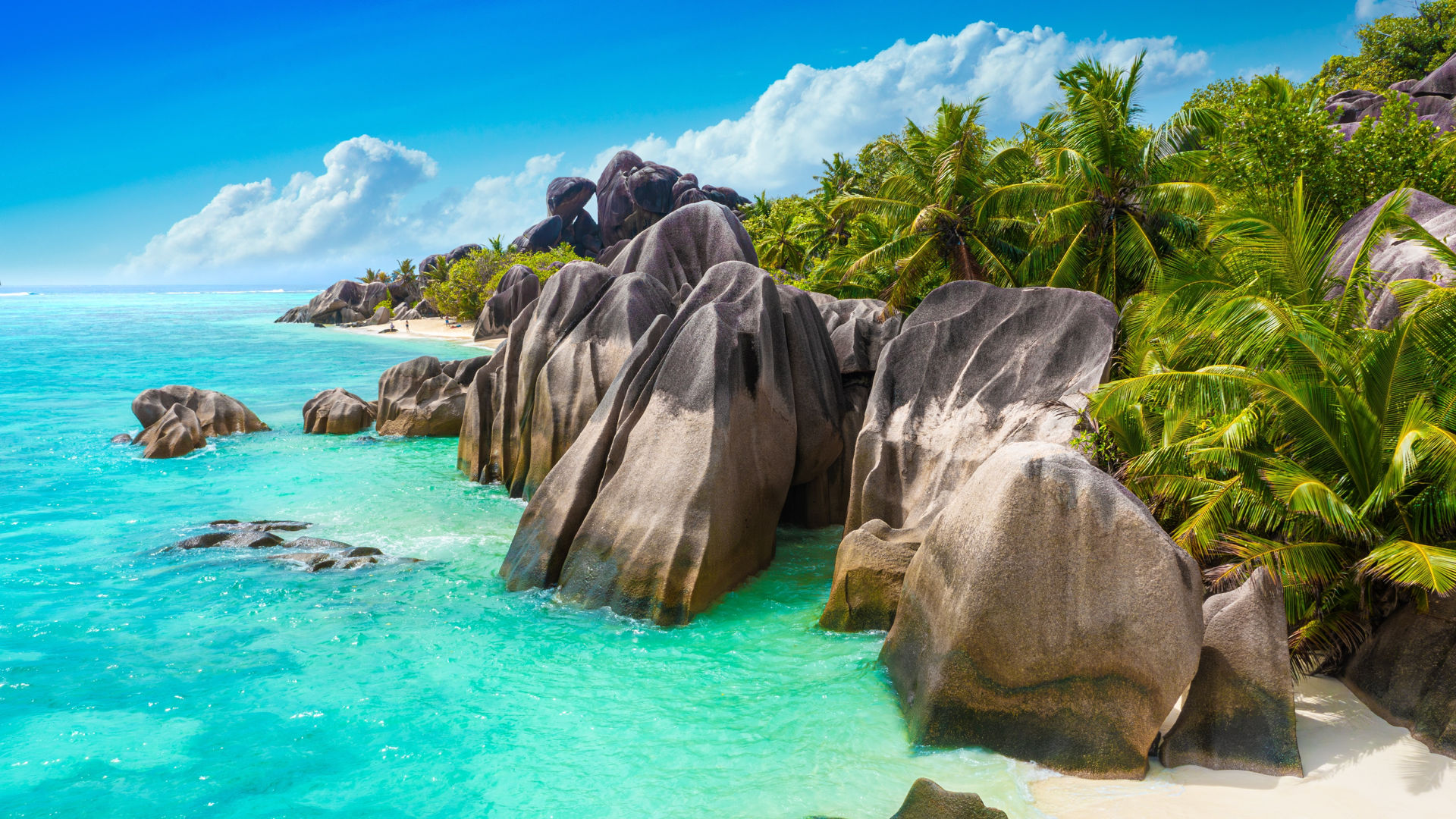 Granitfelsen und Palmen am Strand von La Digue, Seychellen.