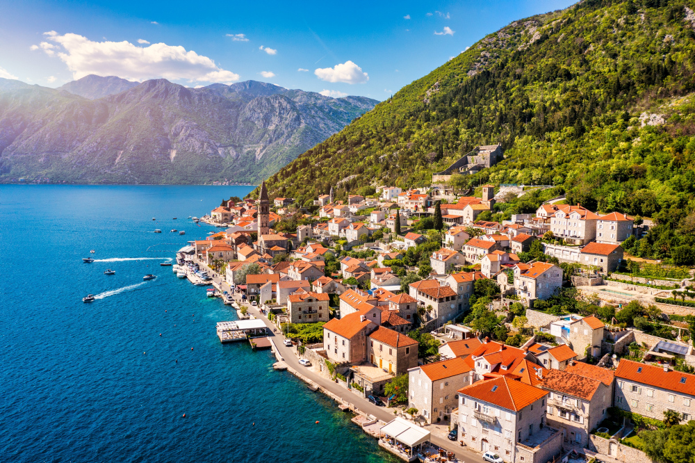 Küstenstadt Perast, Montenegro, mit roten Dächern und Bergen im Hintergrund.