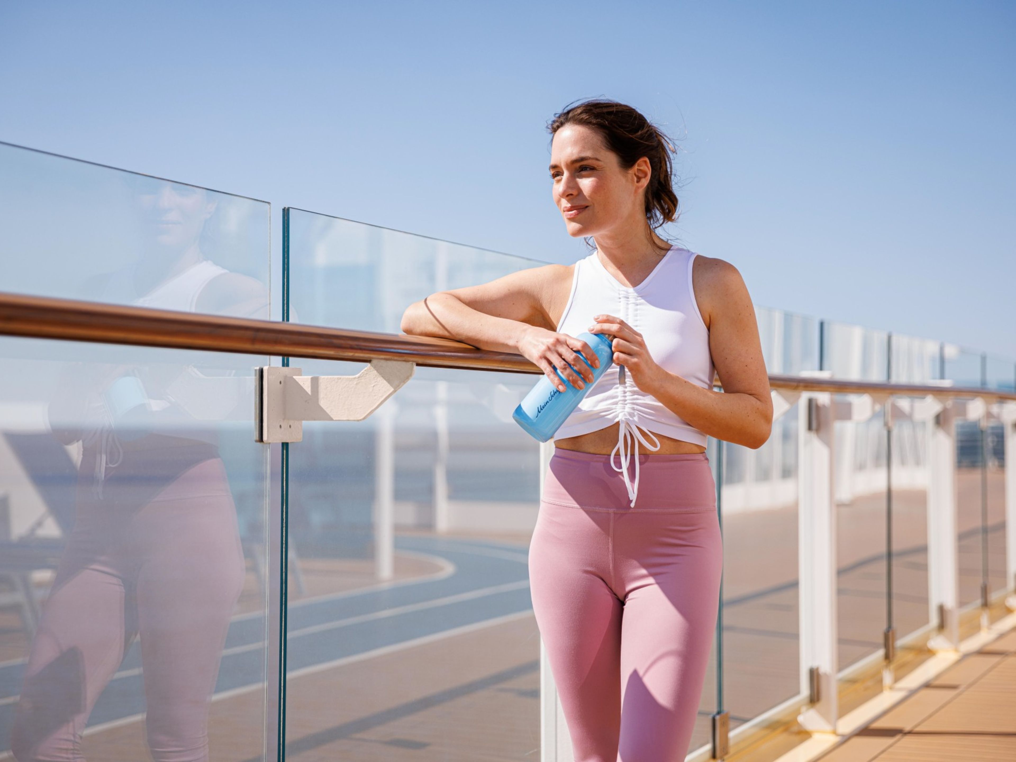 Frau in Sportkleidung mit Wasserflasche auf Kreuzfahrtschiff-Deck. Frau in Sportkleidung mit Wasserflasche auf Kreuzfahrtschiff-Deck.
