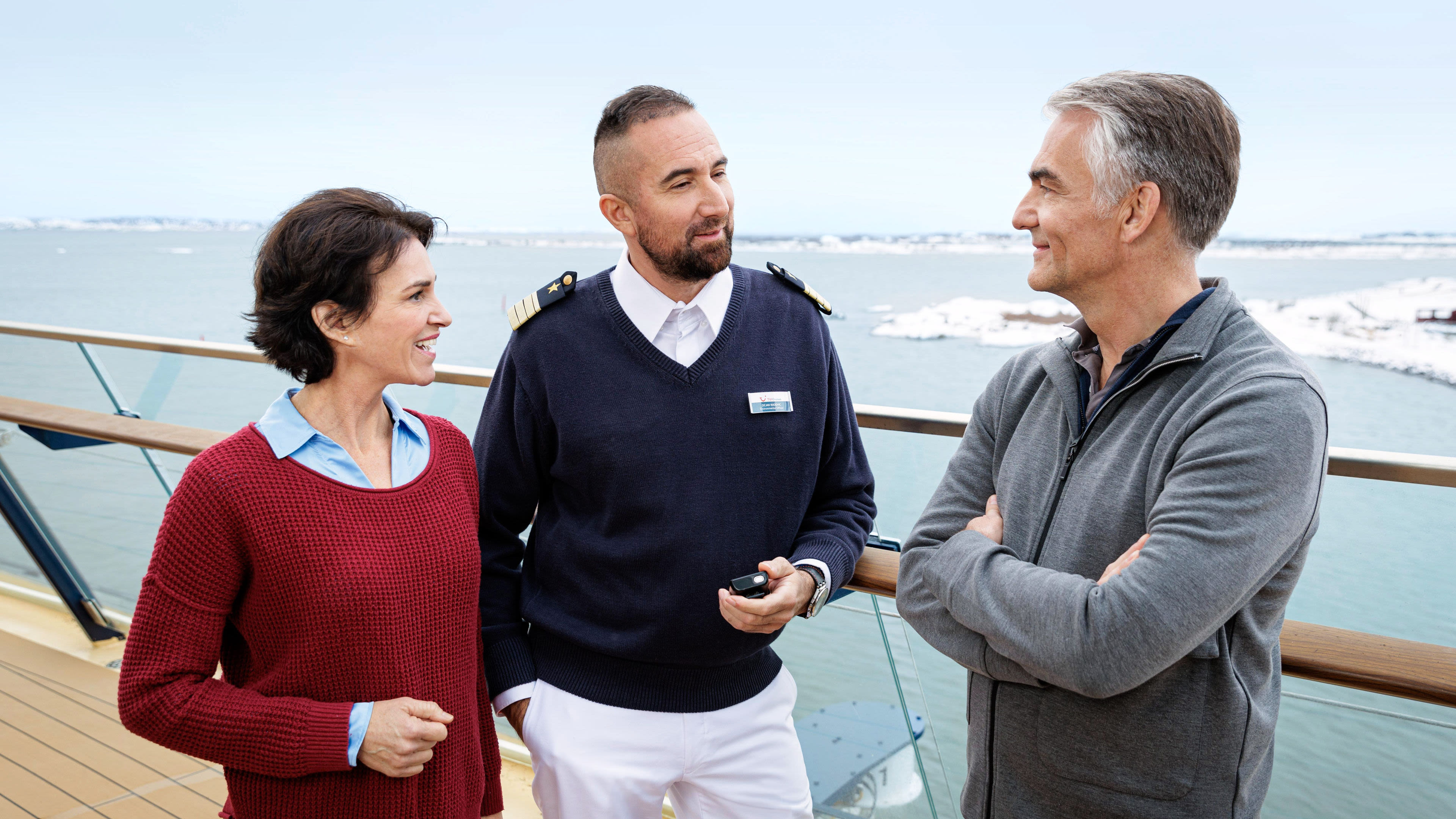 Drei Personen unterhalten sich auf einem Kreuzfahrtschiffdeck.
