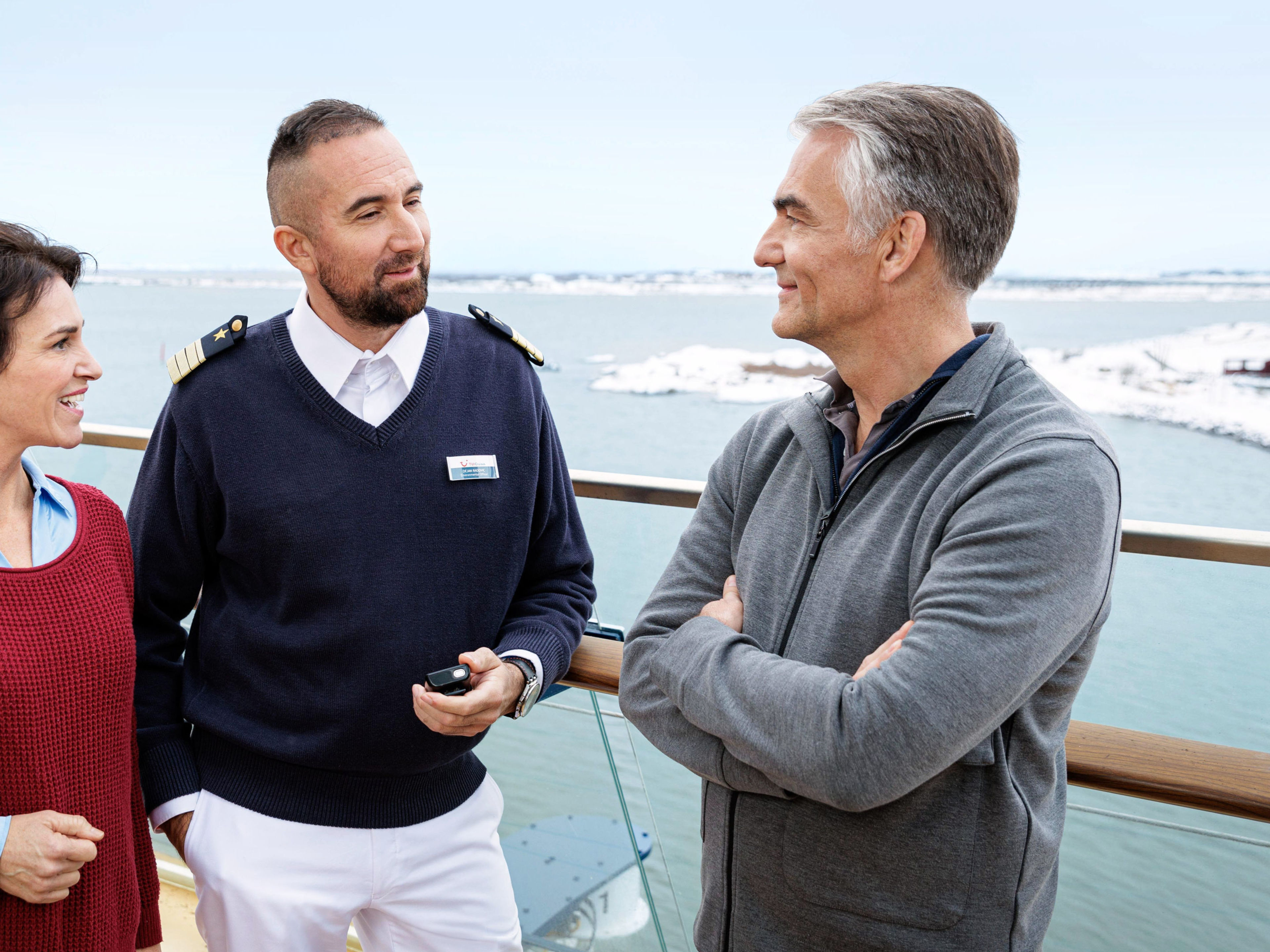 Umweltoffizier unterhält sich mit Gästen Drei Personen unterhalten sich auf einem Kreuzfahrtschiffdeck.
