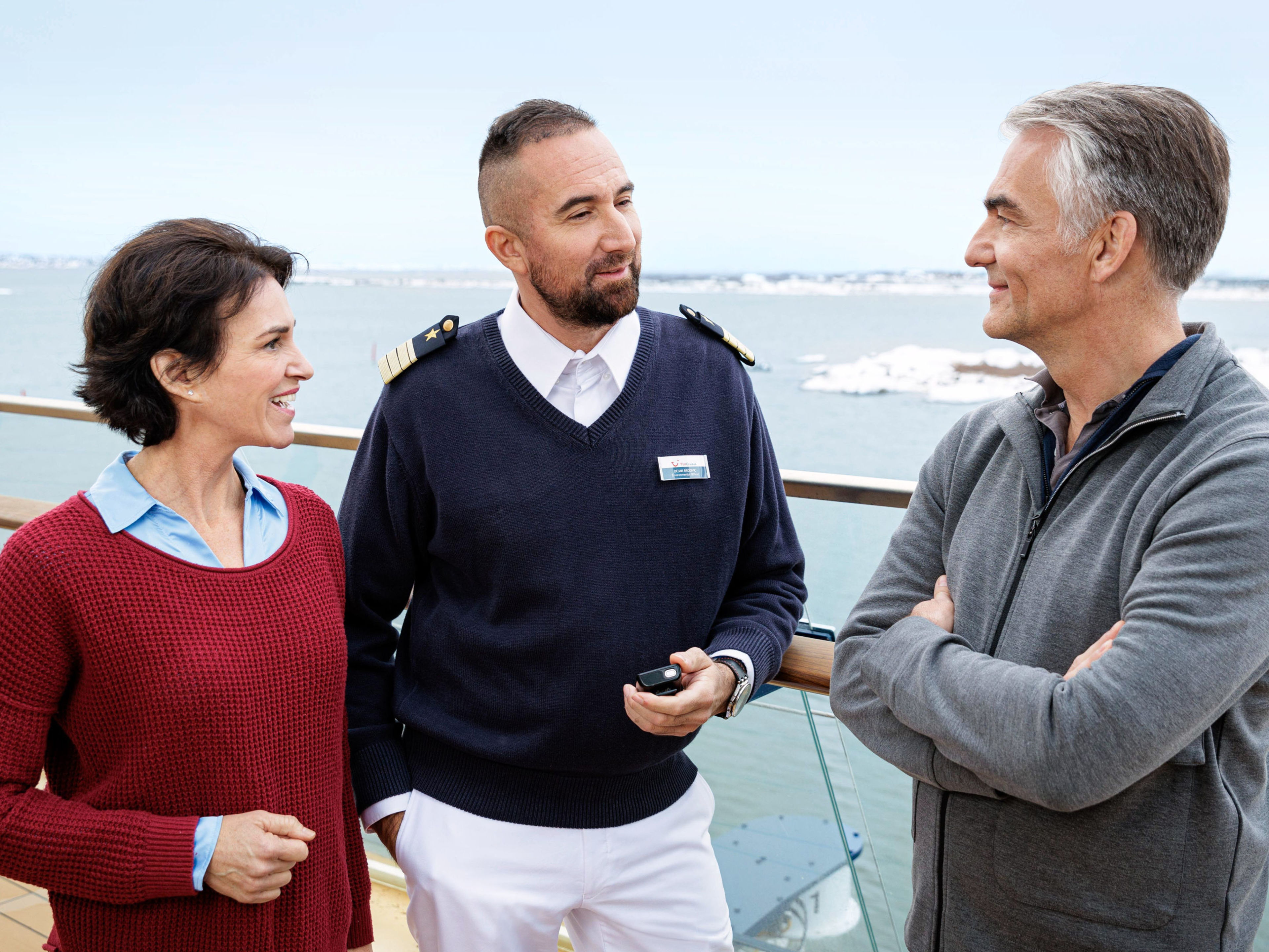 Drei Personen unterhalten sich auf einem Kreuzfahrtschiffdeck. Drei Personen unterhalten sich auf einem Kreuzfahrtschiffdeck.