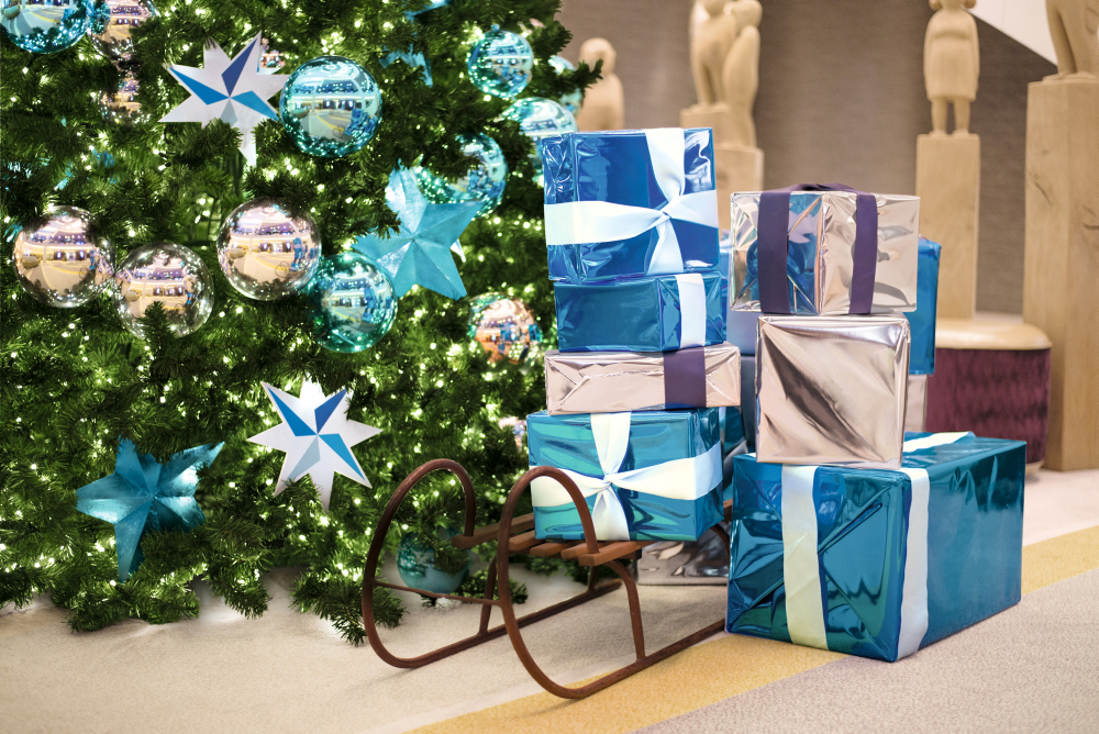 Weihnachtsbaum mit blauen Geschenken und Schlitten.