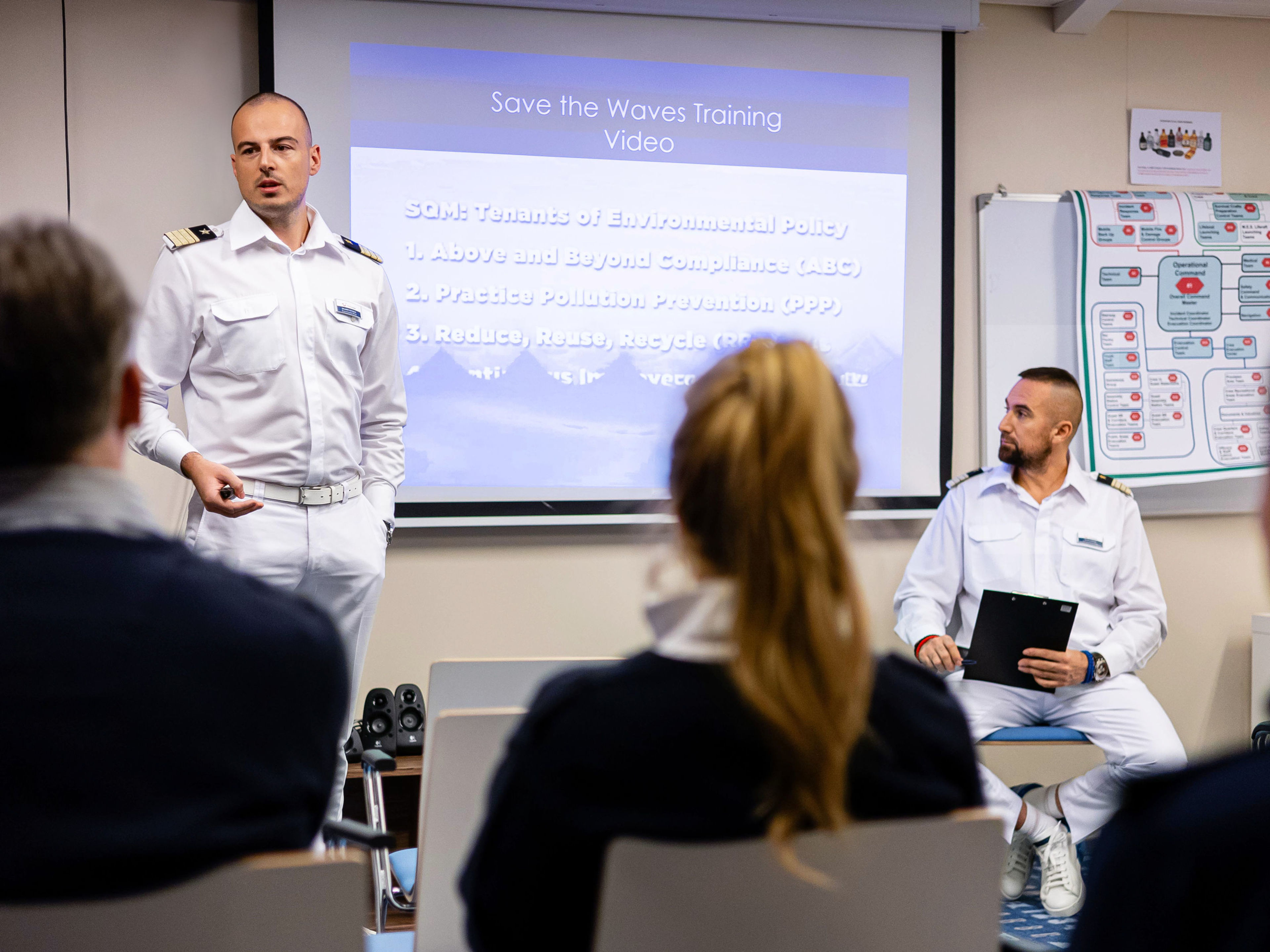 Mann in Uniform hält Vortrag vor Publikum, Präsentation im Hintergrund. Mann in Uniform hält Vortrag vor Publikum, Präsentation im Hintergrund.