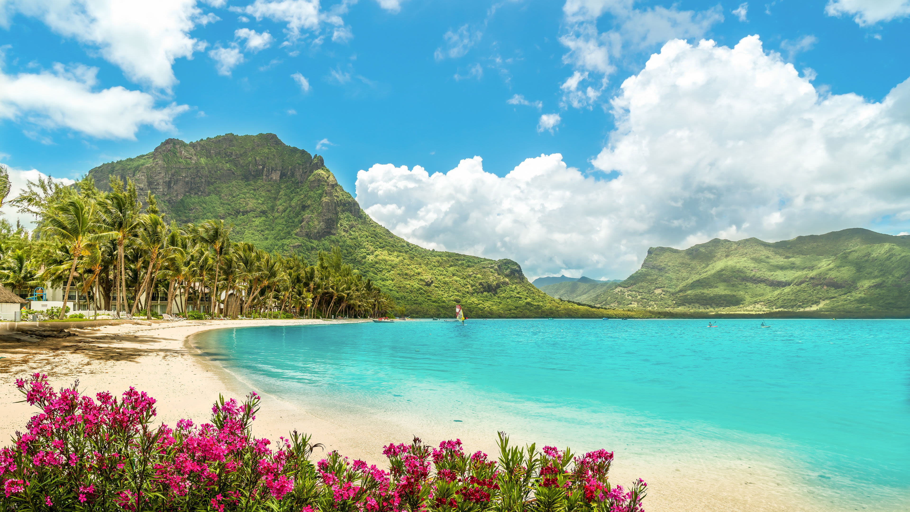 Port Louis - Mauritius Tropischer Strand mit Palmen, türkisfarbenem Wasser und grünen Bergen.