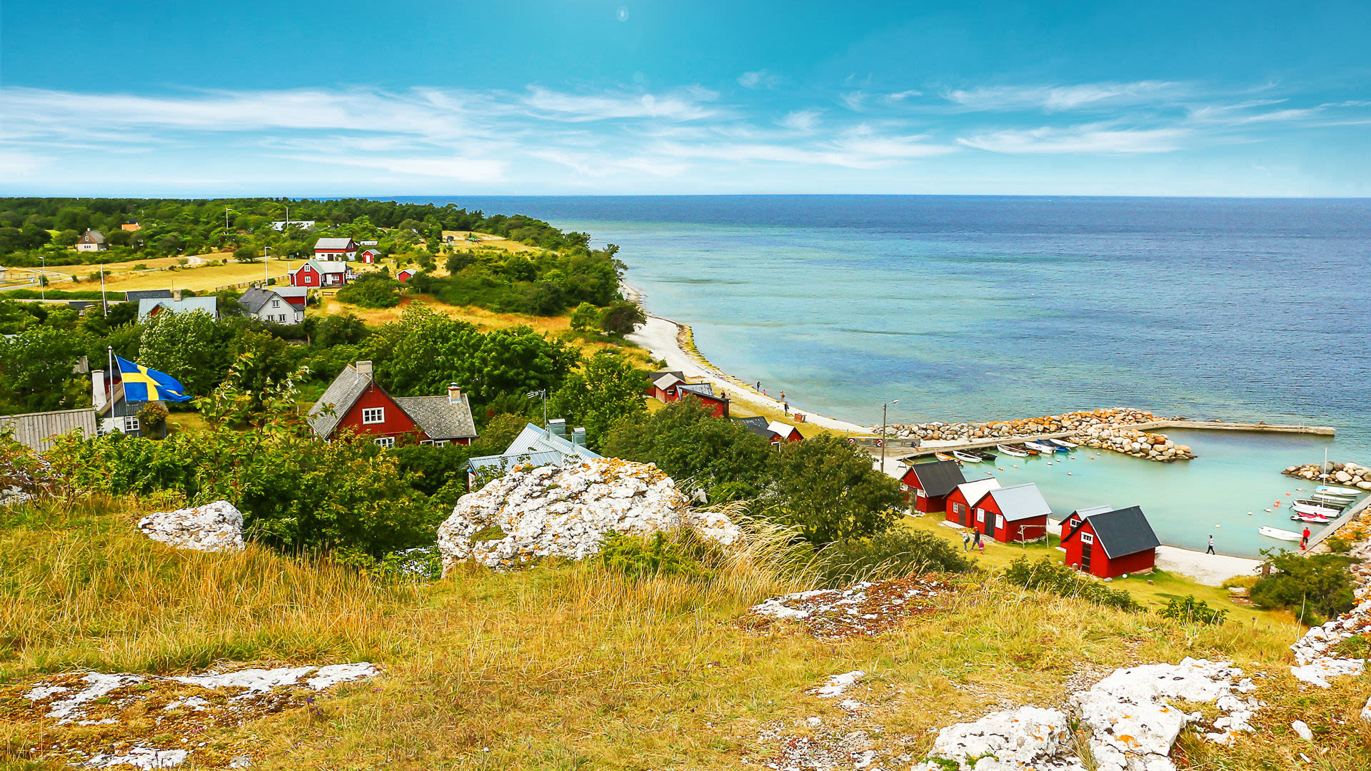 Schwedische Küstenlandschaft mit roten Häusern und blauem Meer.