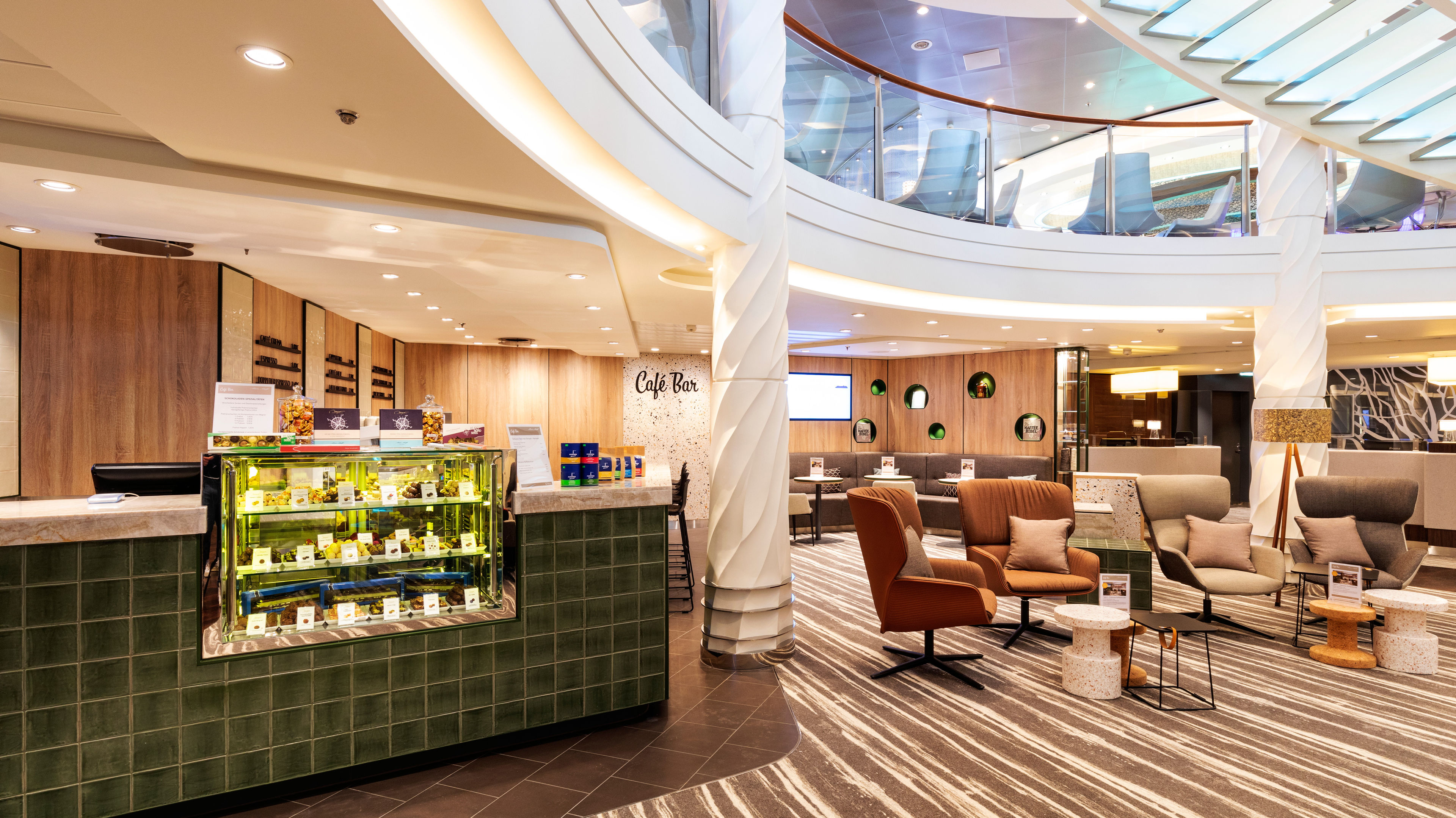 Modernes Café auf Kreuzfahrtschiff der Mein Schiff® Flotte, gemütliche Sitzgelegenheiten.