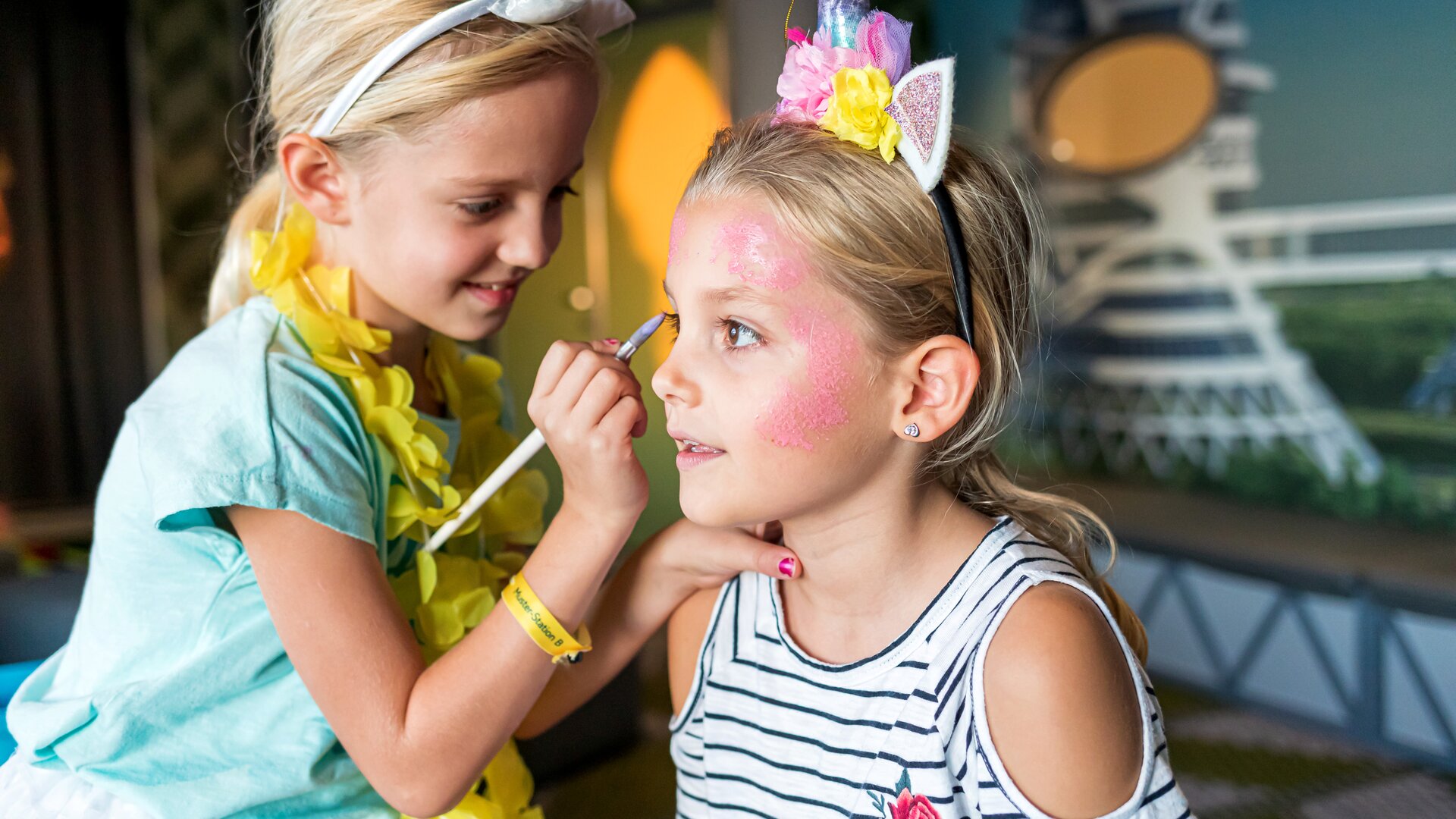 Mädchen schminkt ein anderes mit rosa Farbe, lächelnd.