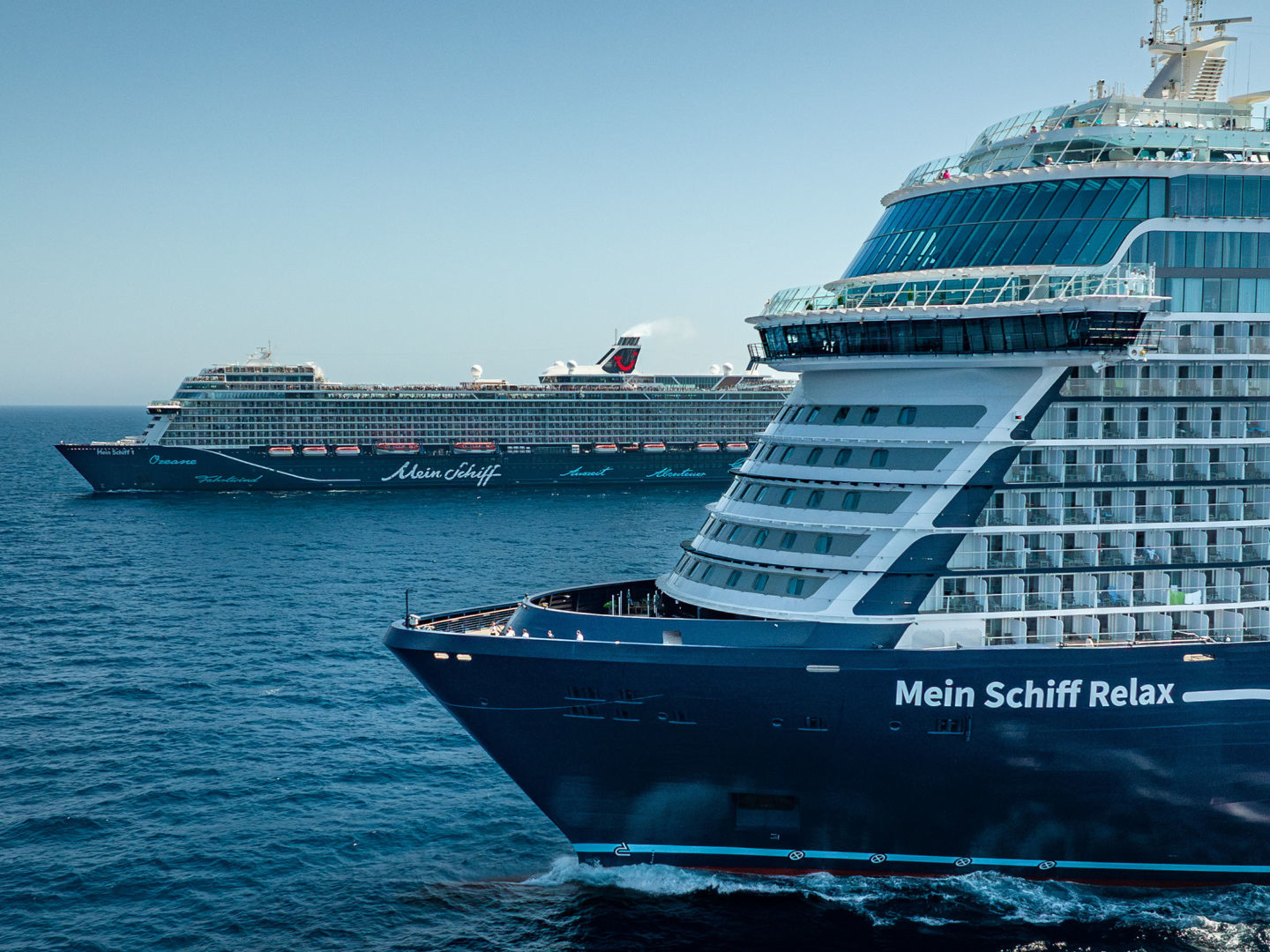 Flottentreffen Mein Schiff Relax und Mein Schiff 1 Zwei Kreuzfahrtschiffe der Mein Schiff® Flotte auf offenem Meer.
