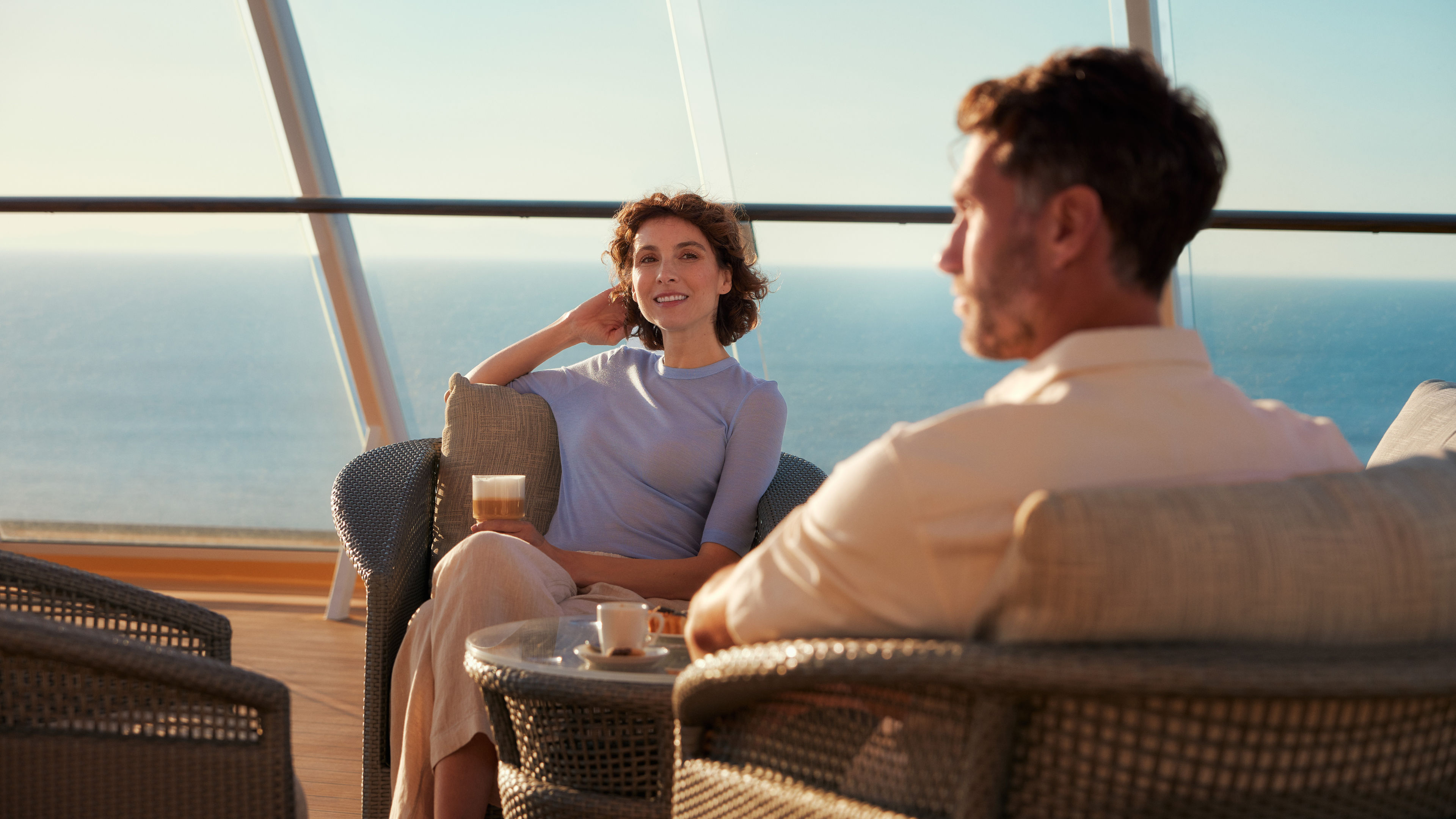 Paar genießt Kaffee auf Kreuzfahrtschiff der Mein Schiff® Flotte mit Meerblick.