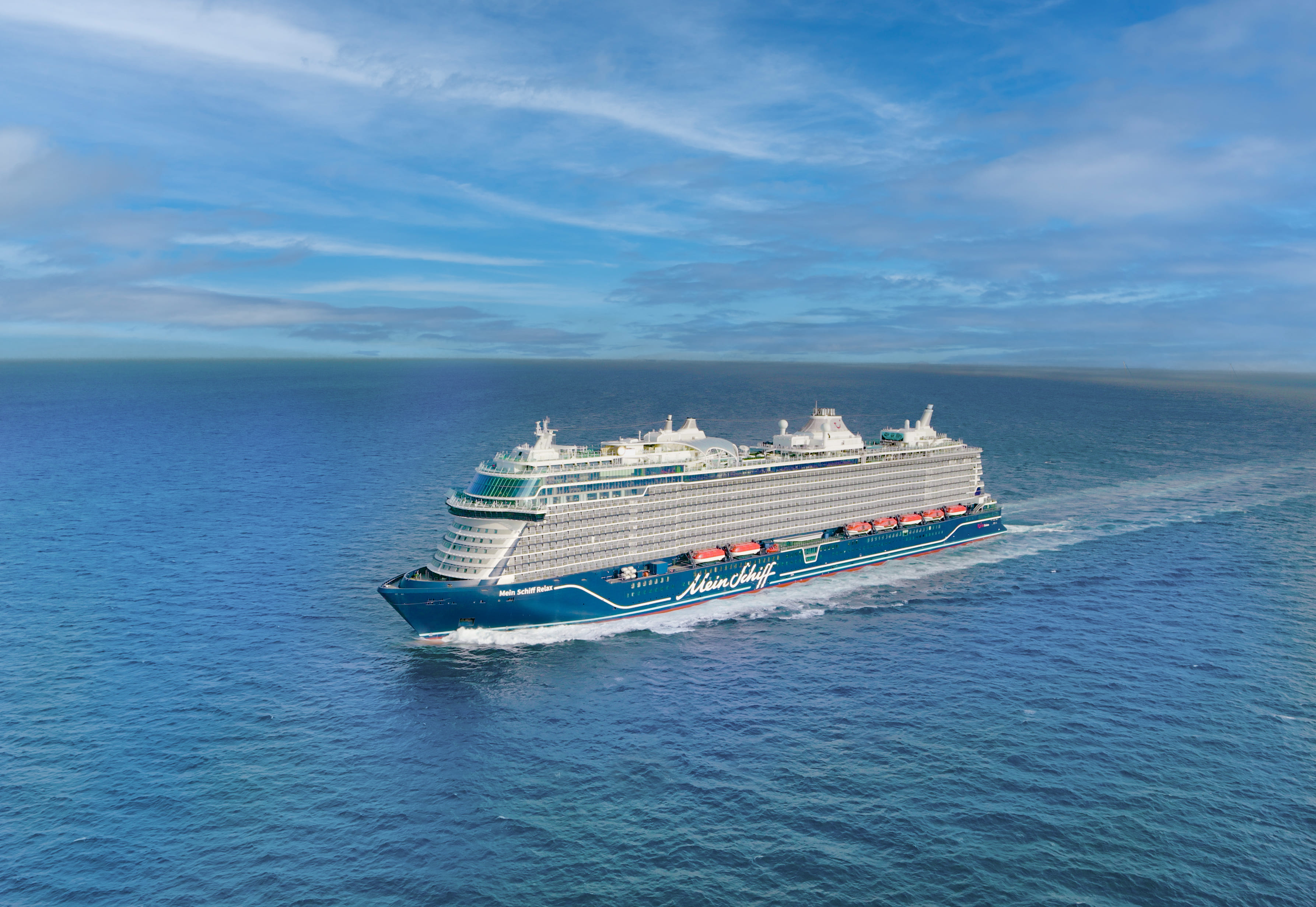 Kreuzfahrtschiff der Mein Schiff® Flotte auf offenem Meer unter blauem Himmel.